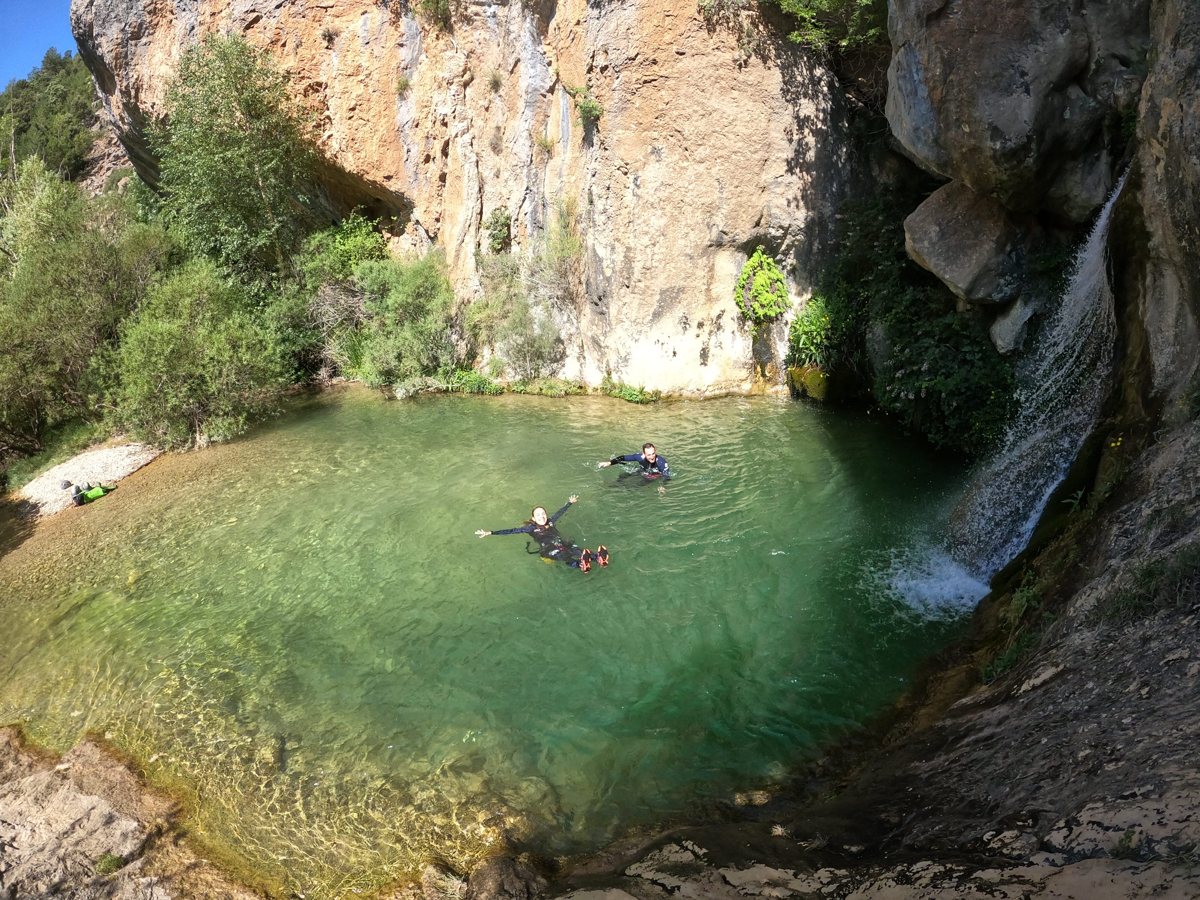Barrancos del Pallars Jussà: participantes disfrutando de una poza de aguas cristalinas junto a una cascada durante una ruta de barranquismo en el Prepirineo de Lleida.