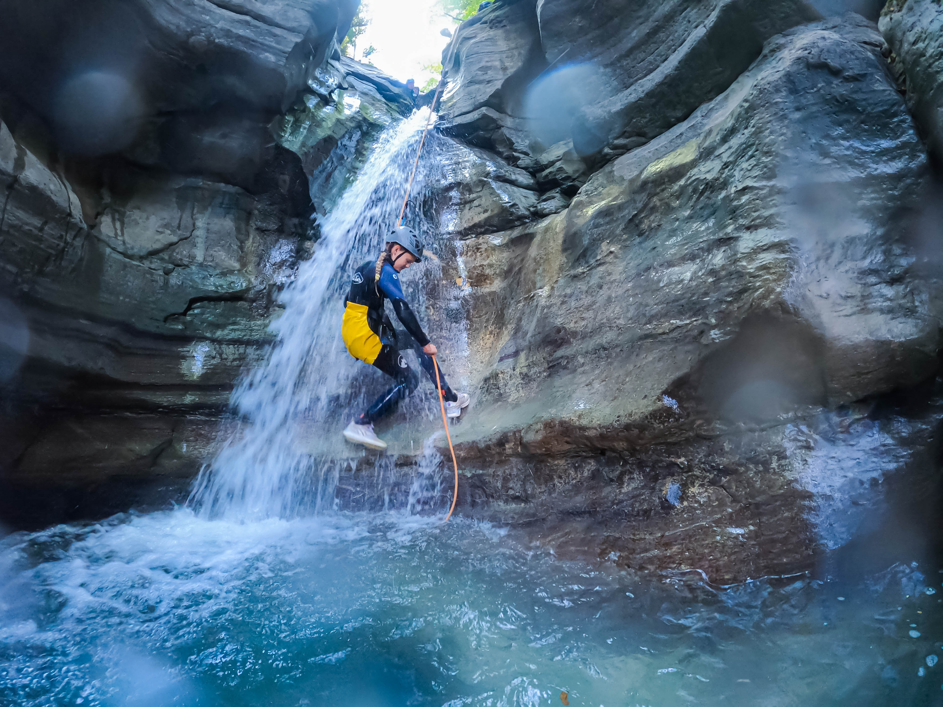 Barrancos del Pallars Jussà: participante realizando un rápel bajo una cascada hacia una poza de aguas turquesas durante una ruta de barranquismo en el Prepirineo de Lleida.