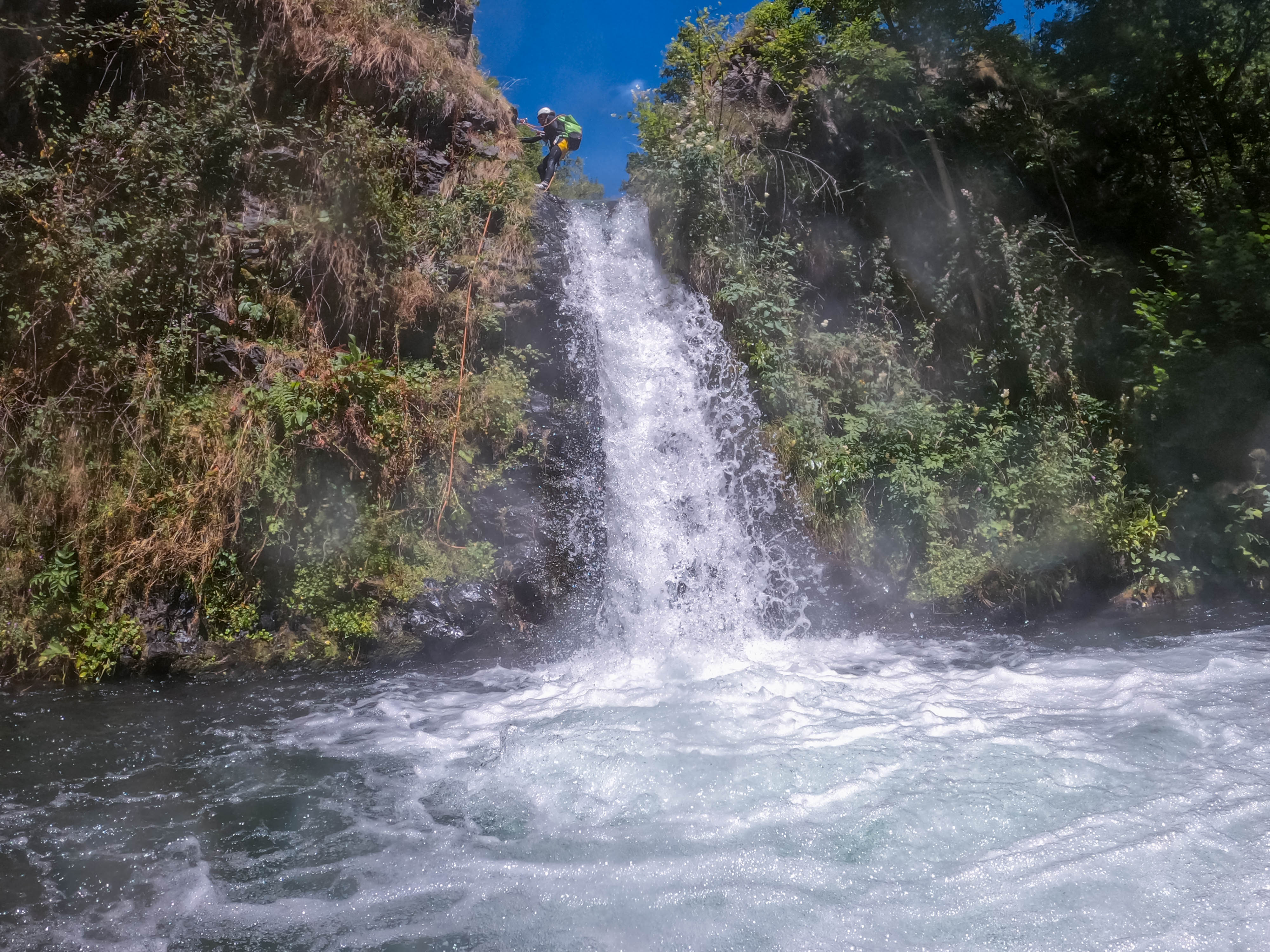 Barrancos del Pallars Jussà: participante realizando un rápel por una cascada de varios metros rodeada de vegetación durante una ruta de barranquismo en el Prepirineo de Lleida.
