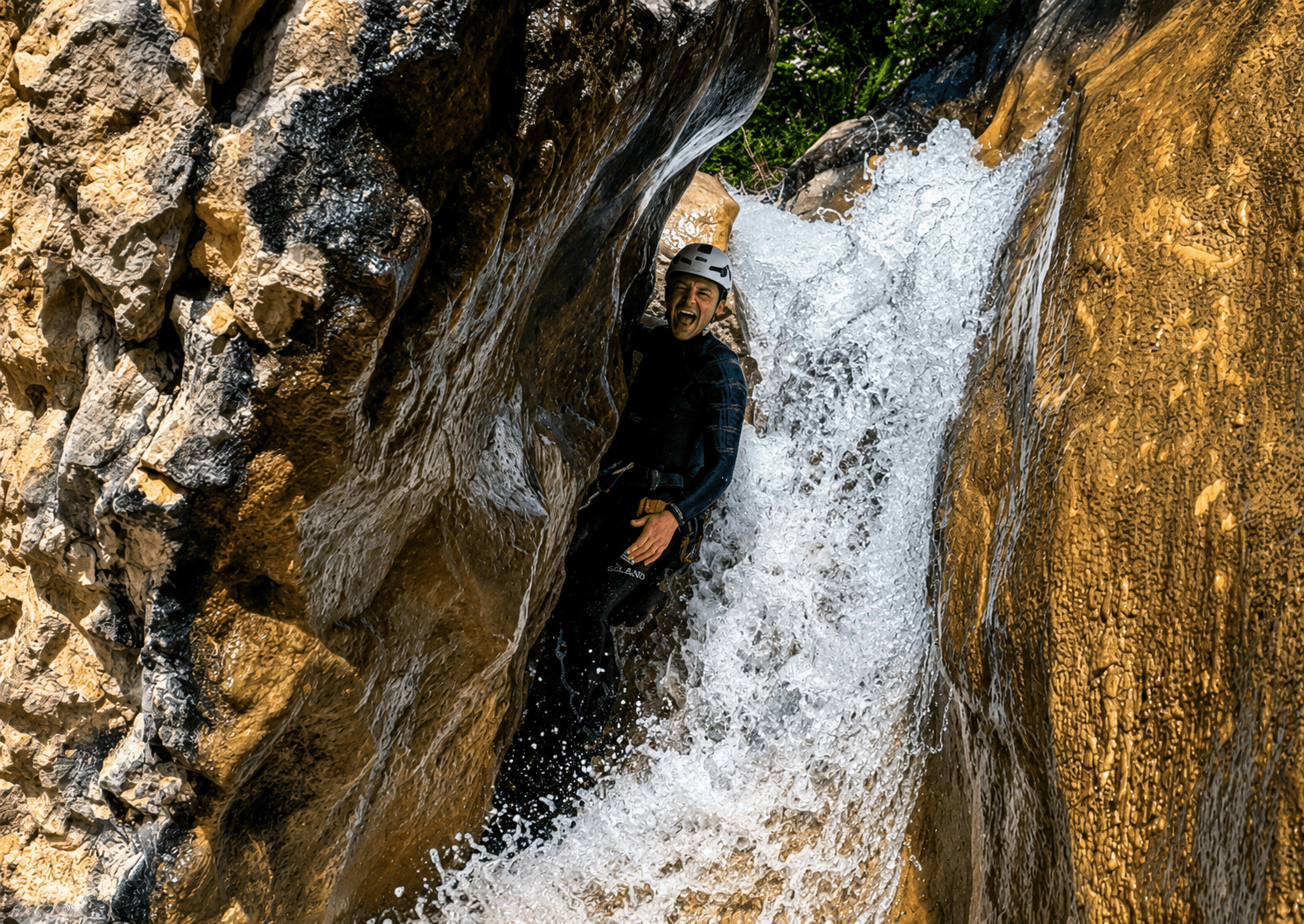 Barranquismo en el Pallars Jussà: participante descendiendo por una estrecha cascada entre paredes de roca durante una emocionante ruta de barranquismo en el Prepirineo de Lleida.