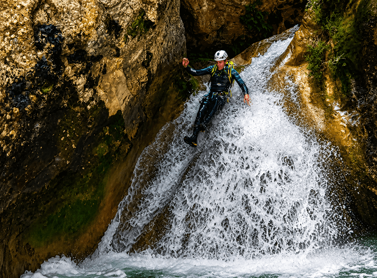 Barrancos del Pallars Jussà: participantes disfrutando de una poza de aguas cristalinas junto a una cascada durante una ruta de barranquismo en el Prepirineo de Lleida. Alt: Barrancos del Pallars Jussà: participante deslizándose por una cascada natural entre paredes de roca durante una ruta de barranquismo en el Prepirineo de Lleida.