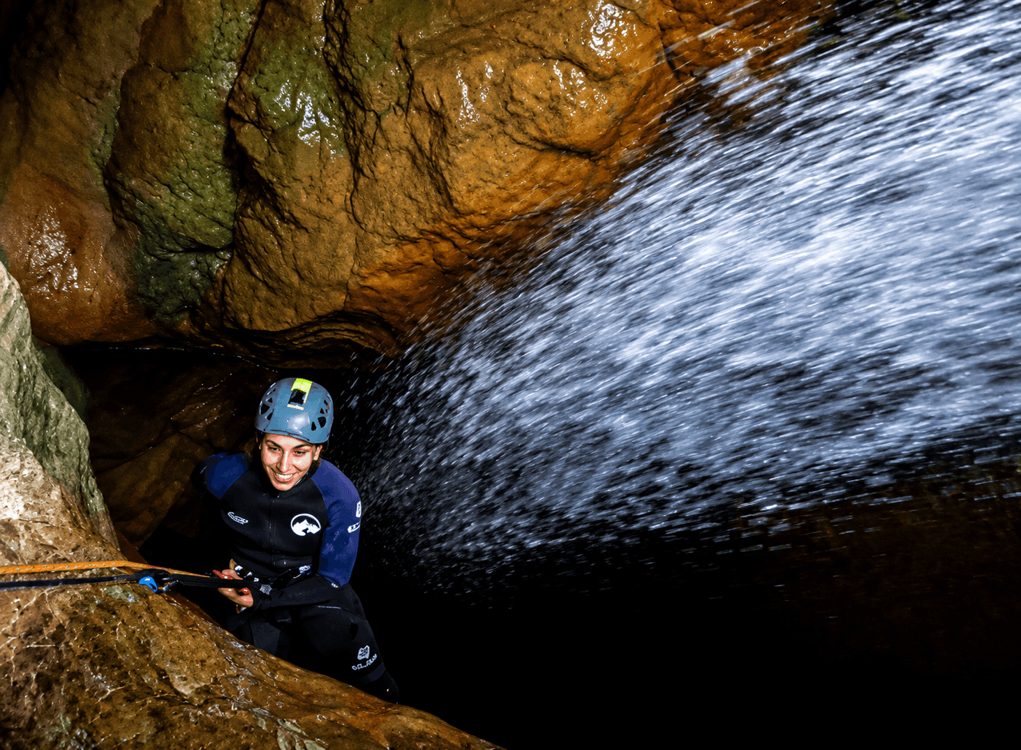 Barranquismo en el Pallars Jussà: participante realizando un rápel junto a una cascada en un estrecho cañón de roca durante una ruta de barranquismo en el Prepirineo de Lleida.