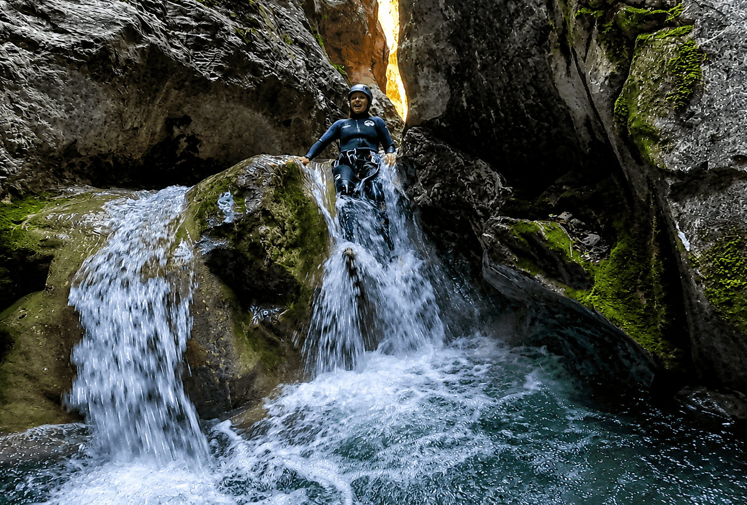 Barrancos del Pallars Jussà: participante descendiendo por un tobogán natural entre estrechas paredes de roca y cascadas durante una ruta de barranquismo en el Prepirineo de Lleida.