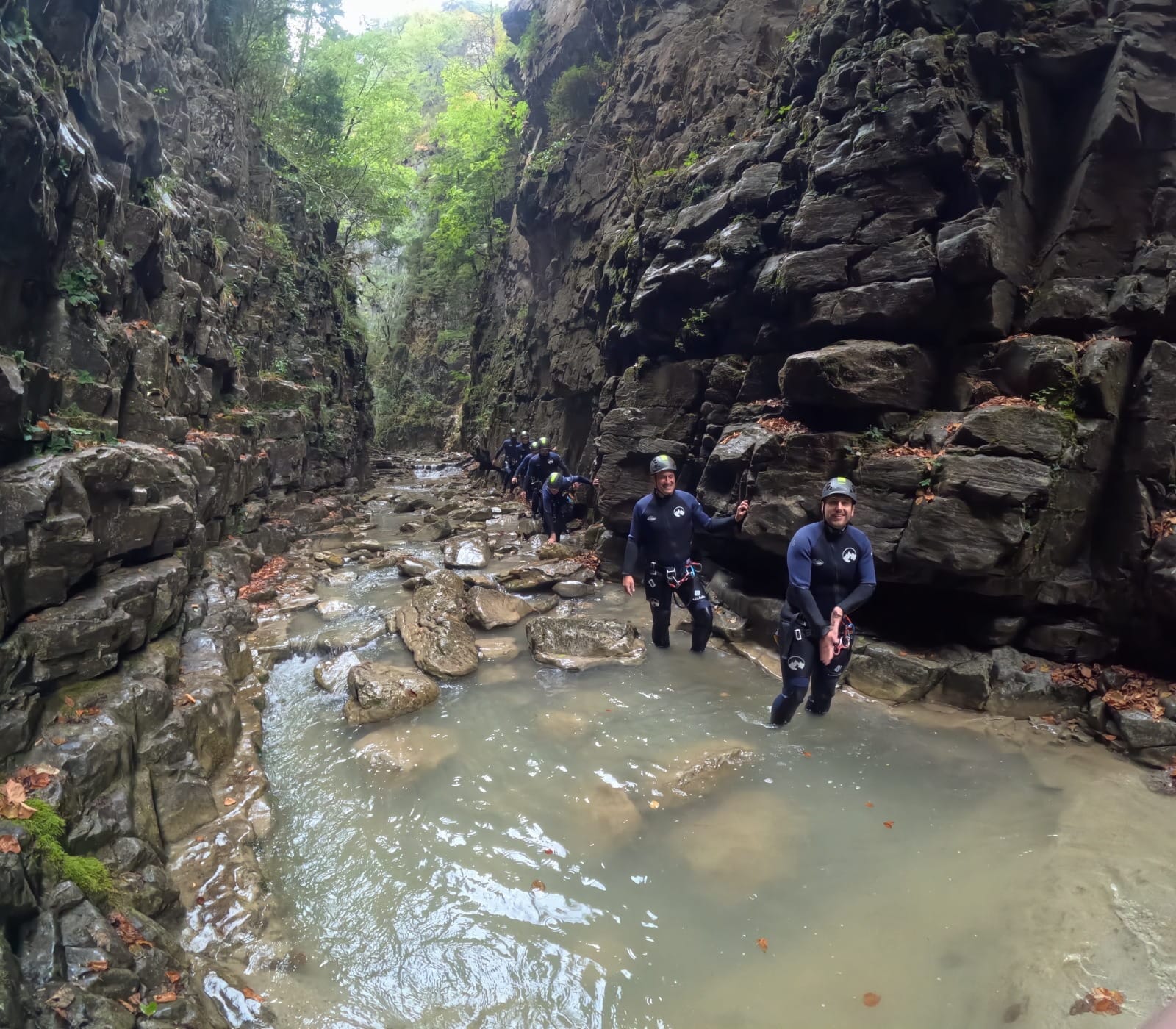 Grupo de participantes de barranquismo avanzando por un estrecho desfiladero rocoso con poca agua en el Barranco de Barbaruens