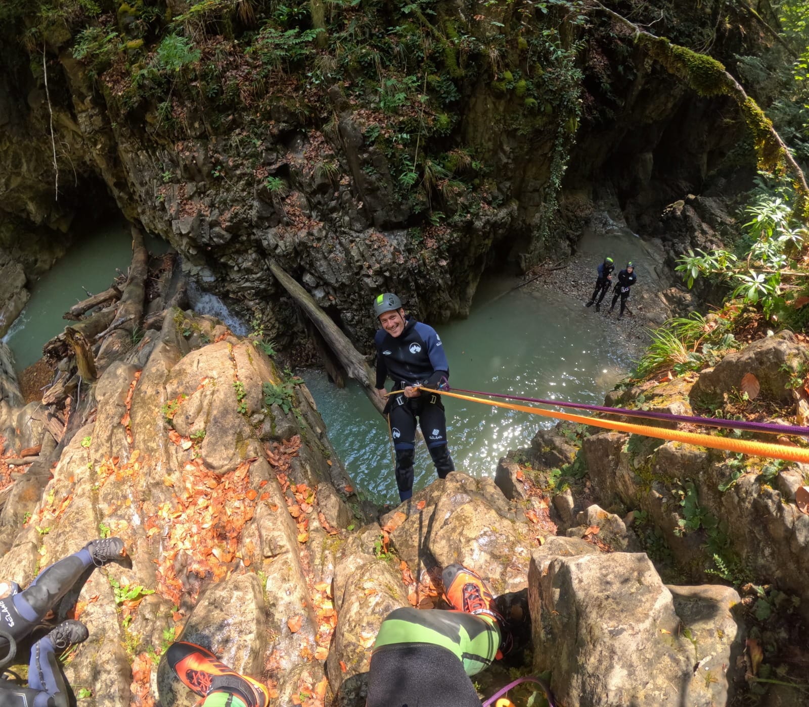 Participante de barranquismo descendiendo en rápel por un tramo rocoso sobre una poza natural en el Barranco de Barbaruens