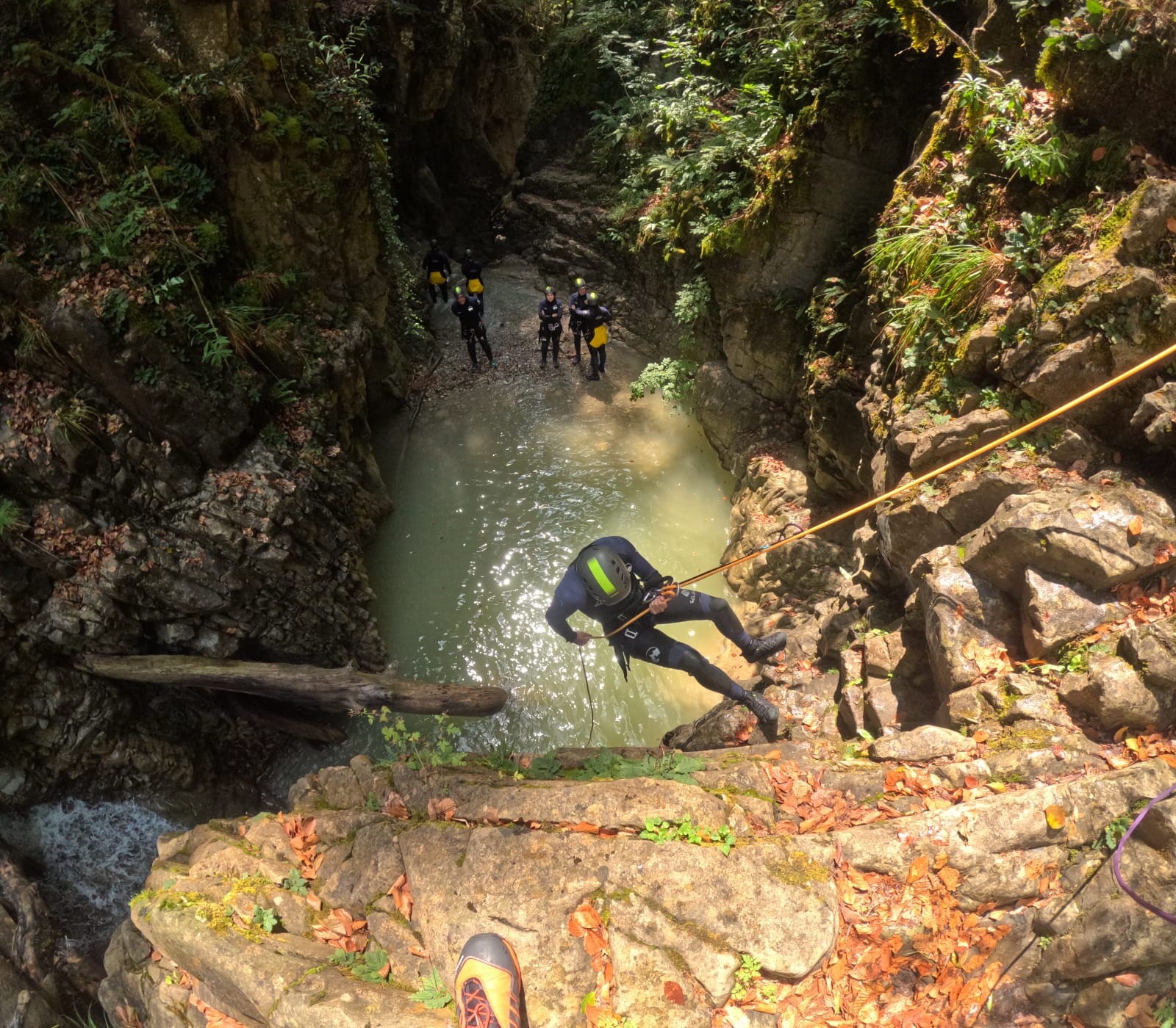 Participante de barranquismo descendiendo en rápel por una pared rocosa hacia una poza natural en el Barranco de Barbaruens