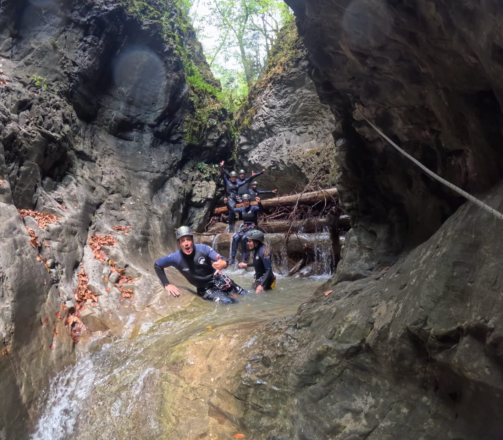 Grupo de participantes de barranquismo descendiendo por un paso estrecho y rocoso con pequeñas cascadas en el Barranco de Barbaruens