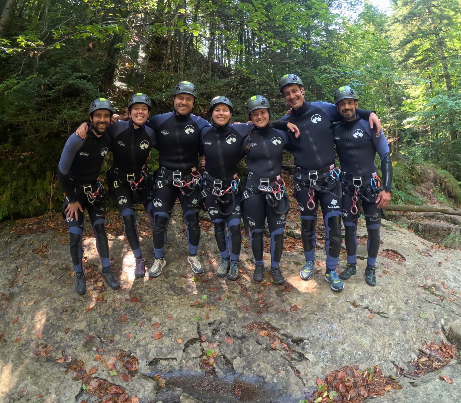Grupo de participantes de barranquismo posando juntos con neoprenos y cascos después de su aventura en el Barranco de Barbaruens