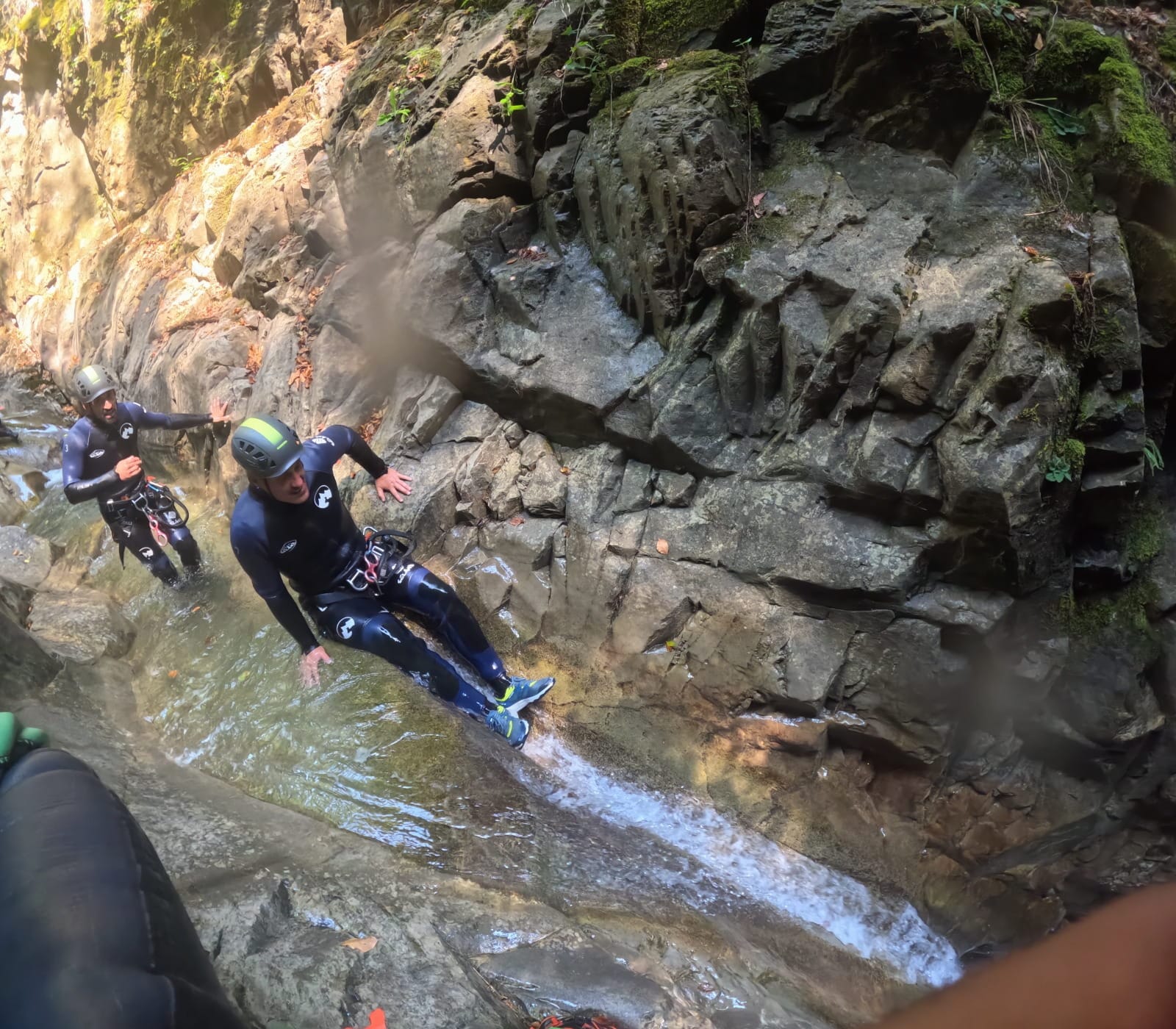 Participantes de barranquismo descendiendo por un tobogán natural de roca en el Barranco de Barbaruens