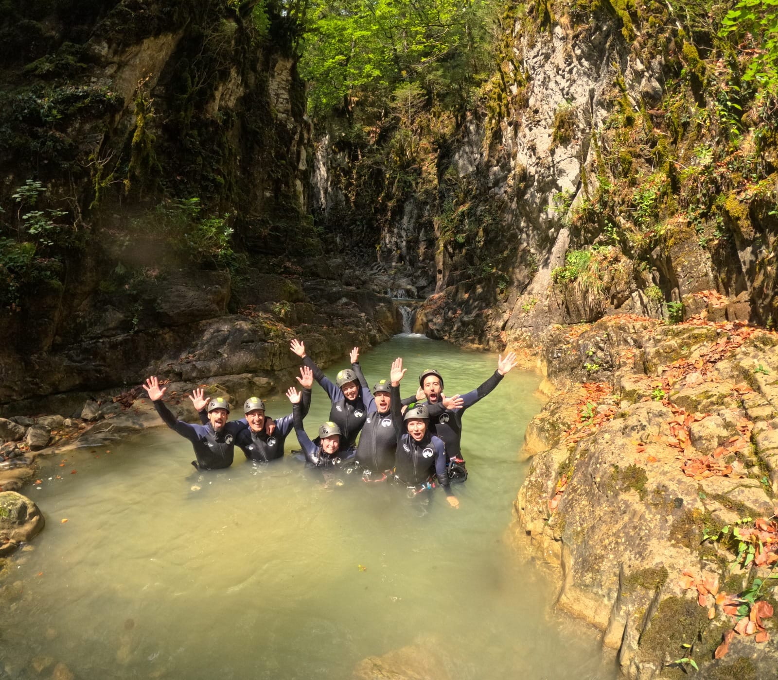 Grupo de participantes de barranquismo celebrando juntos en una poza natural en el Barranco de Barbaruens