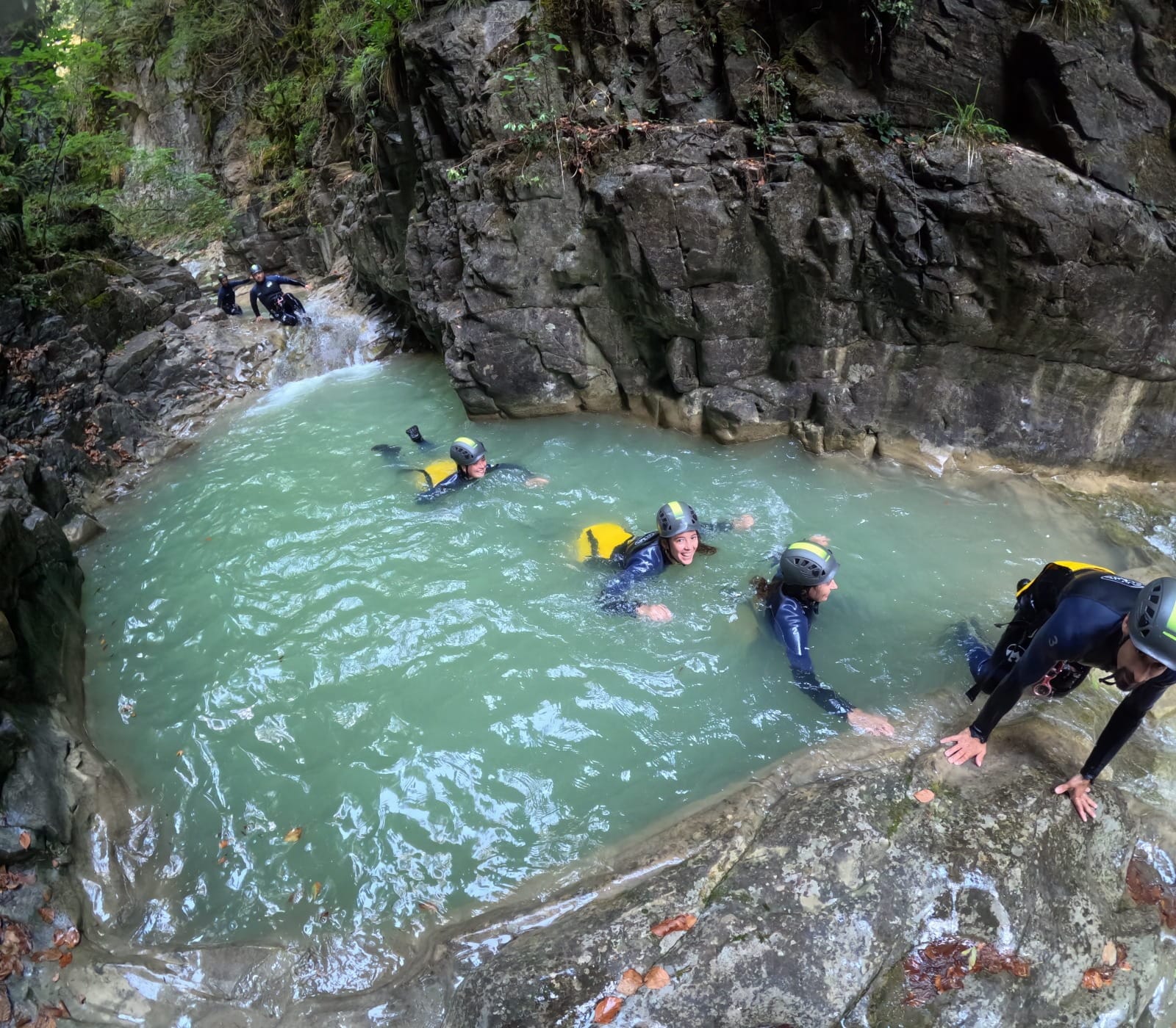 Participantes de barranquismo nedando en una poza natural de aguas turquesas en el Barranco de Barbaruens