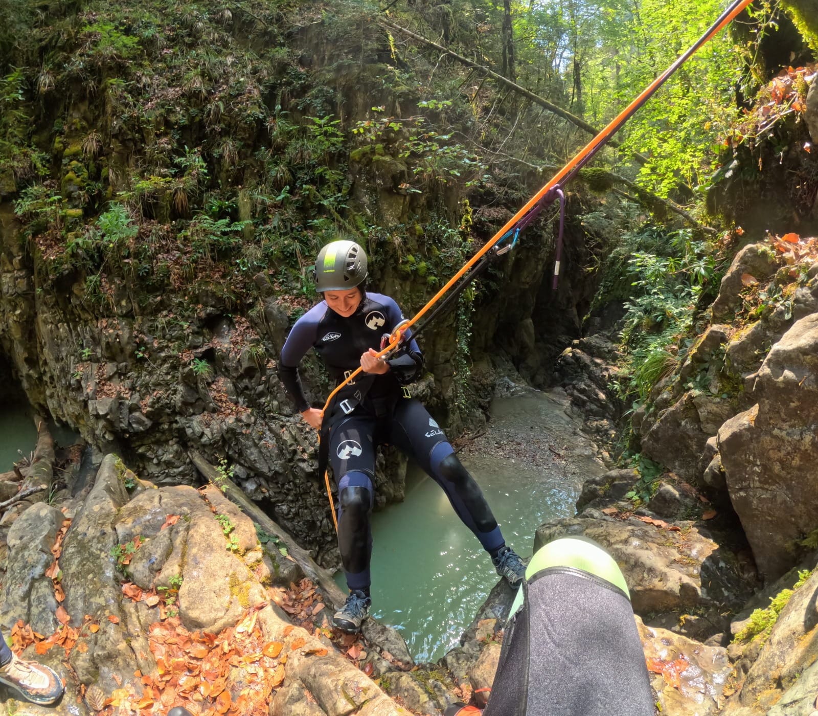 Participante de barranquismo preparándose para hacer rápel sobre una poza natural en el Barranco de Barbaruens