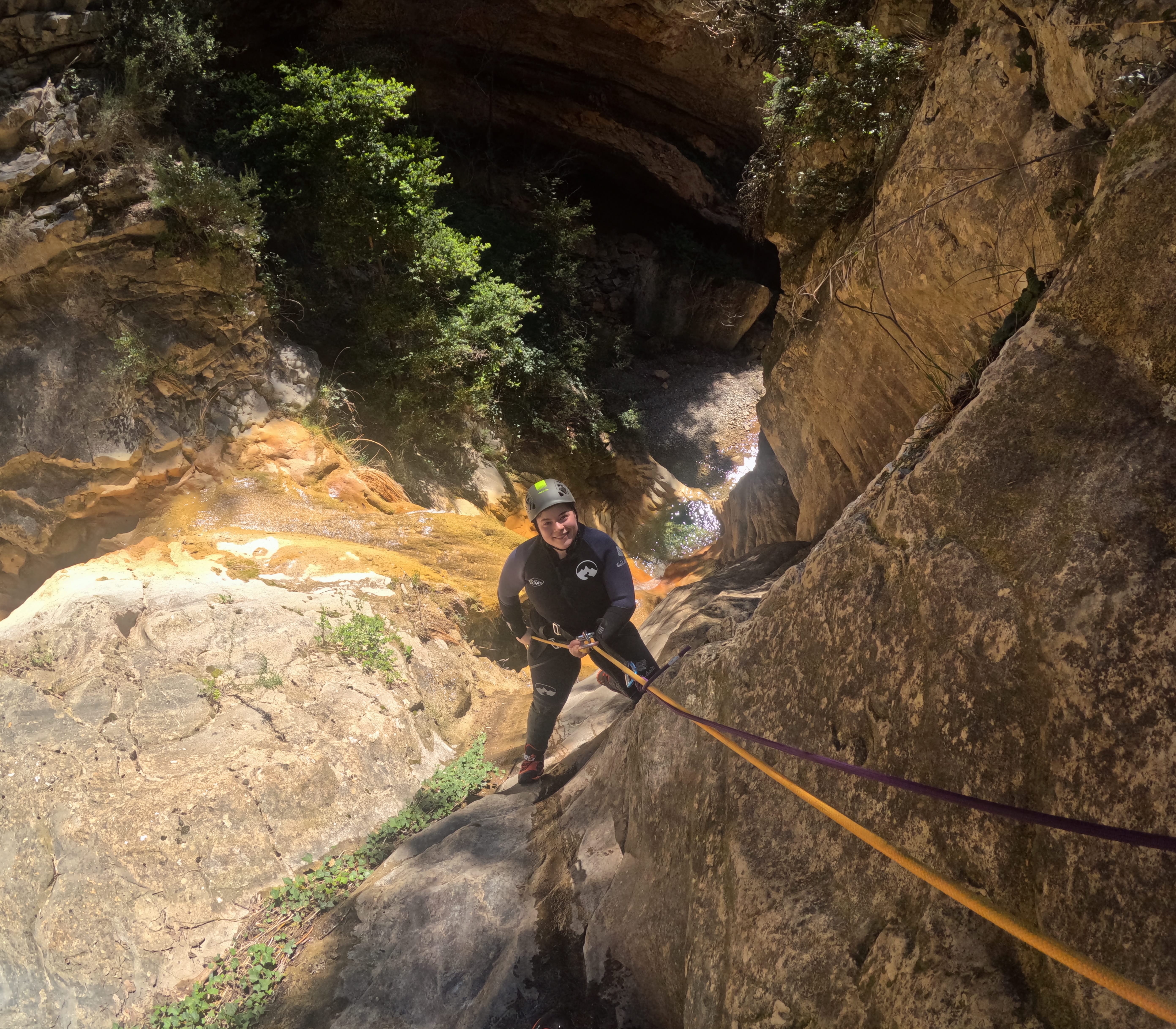 Participant rappelling down a rocky section of Barranco de Gurp surrounded by steep canyon walls