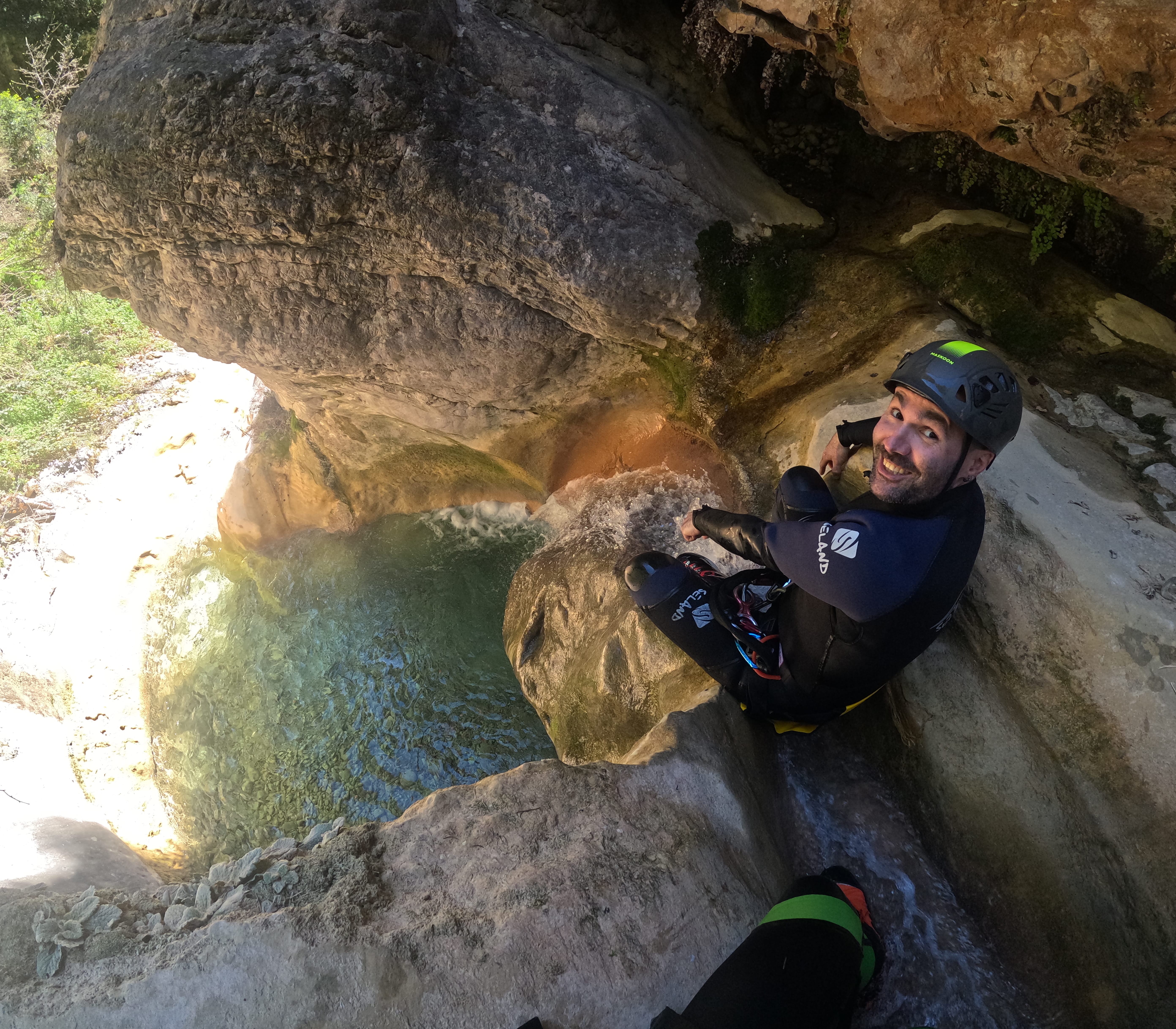 Smiling participant preparing to descend beside a clear natural pool and small waterfall in Barranco de Gurp