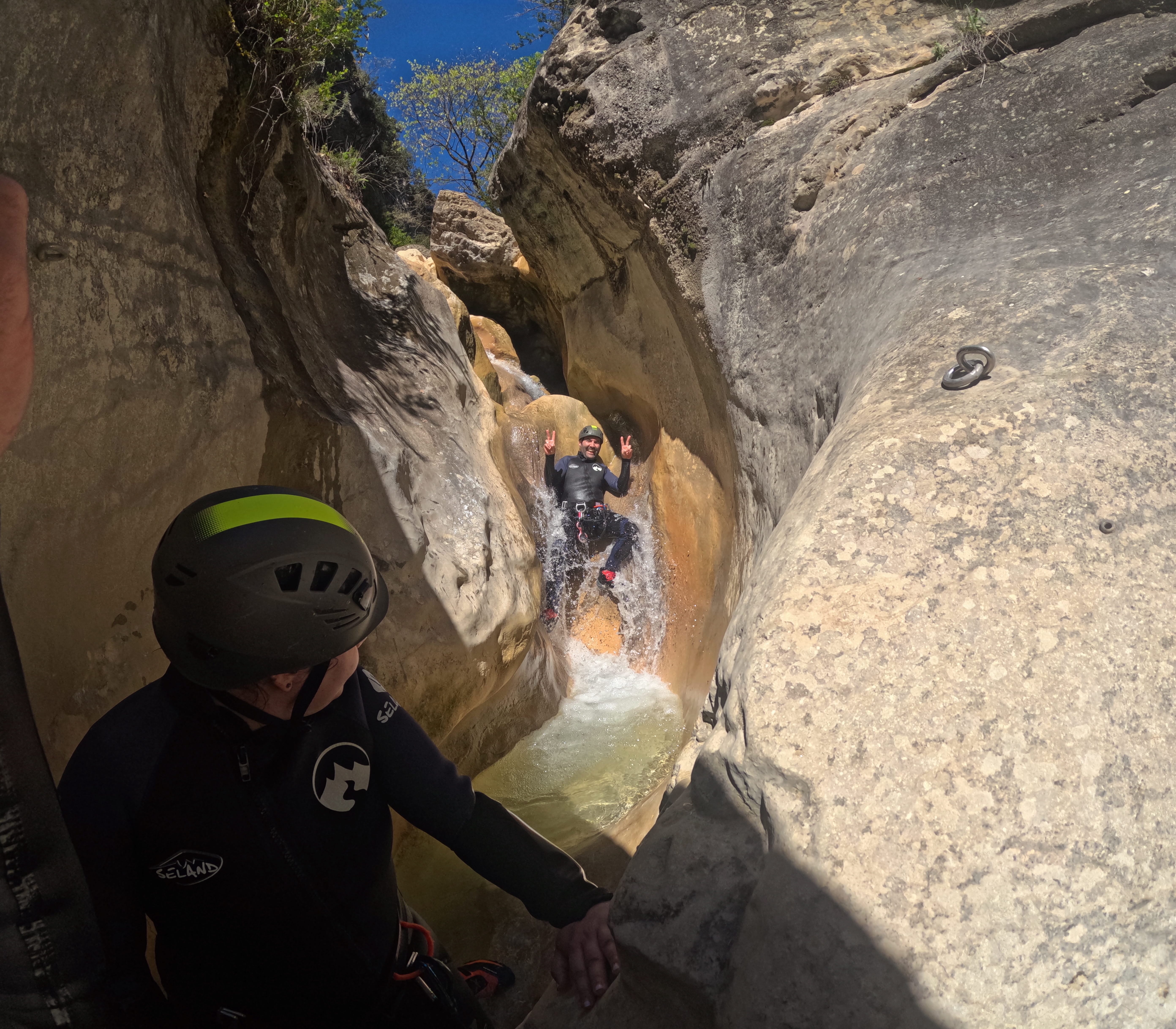 Participant sliding down a small waterfall into a natural pool while canyoning in Barranco de Gurp