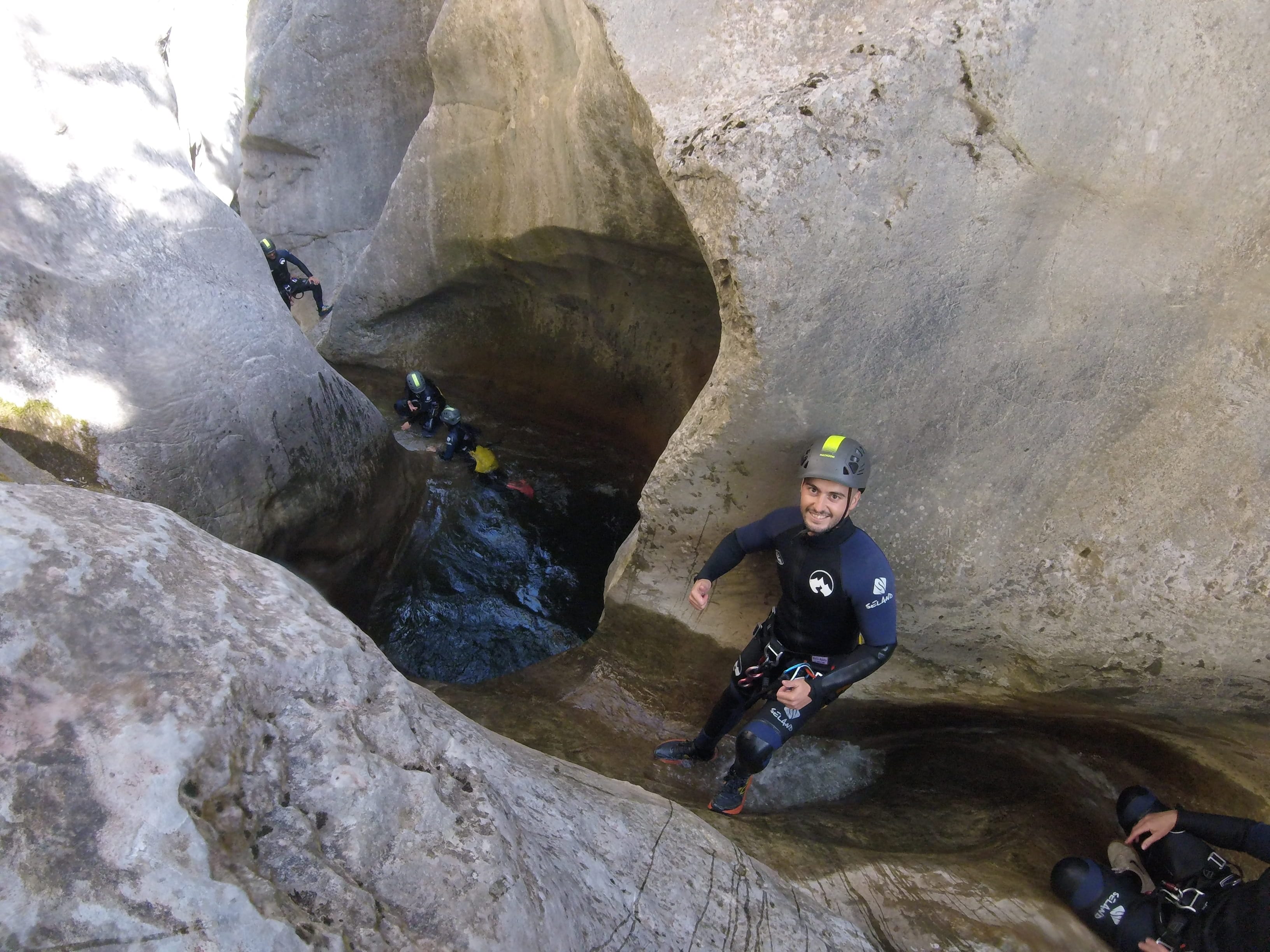 Canyoning participant walking through a sculpted rocky passage with natural pools in Barranc de Viu de Llevata