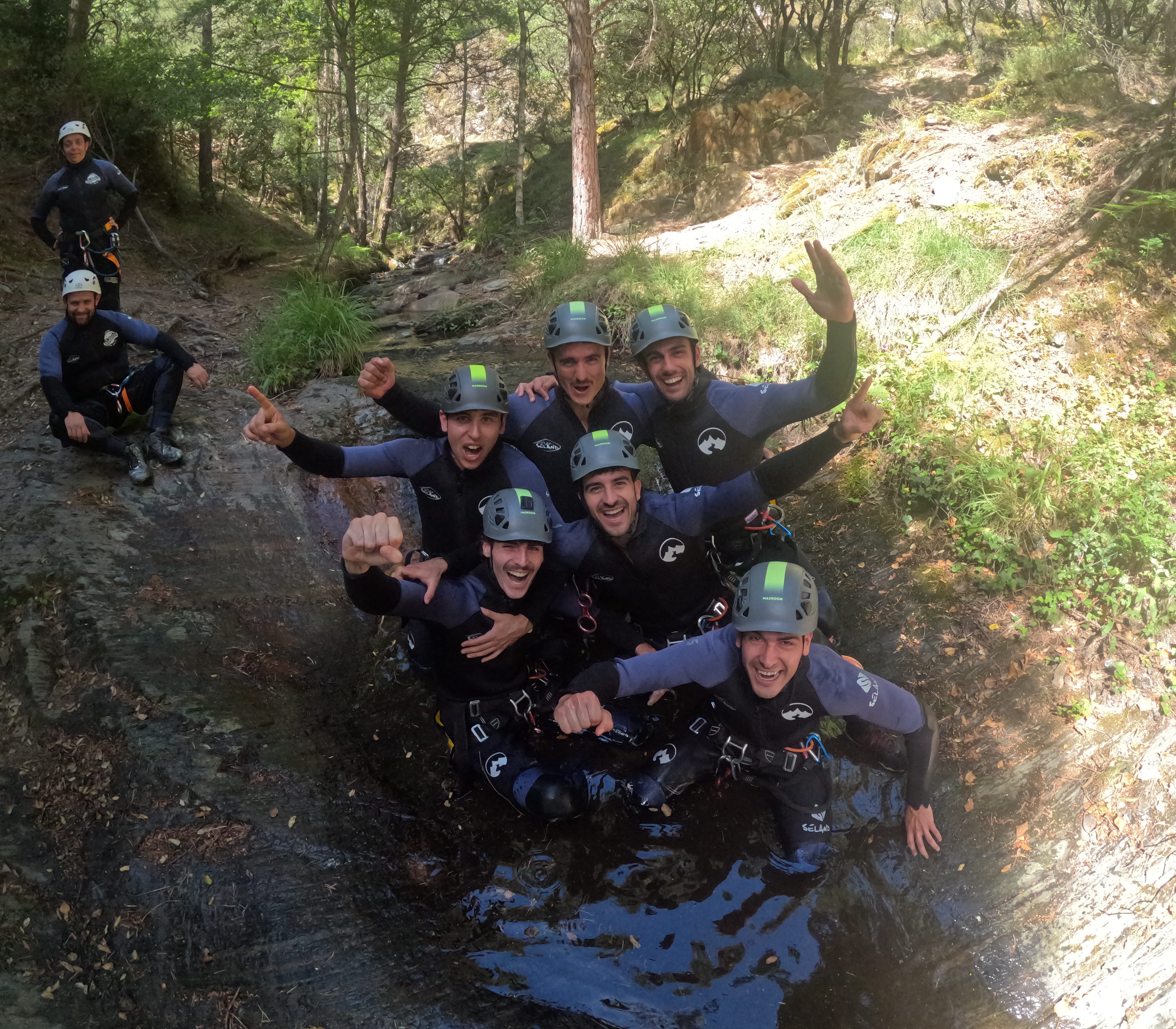 Group of canyoning participants celebrating together in a forest stream in Barranco de Estaron