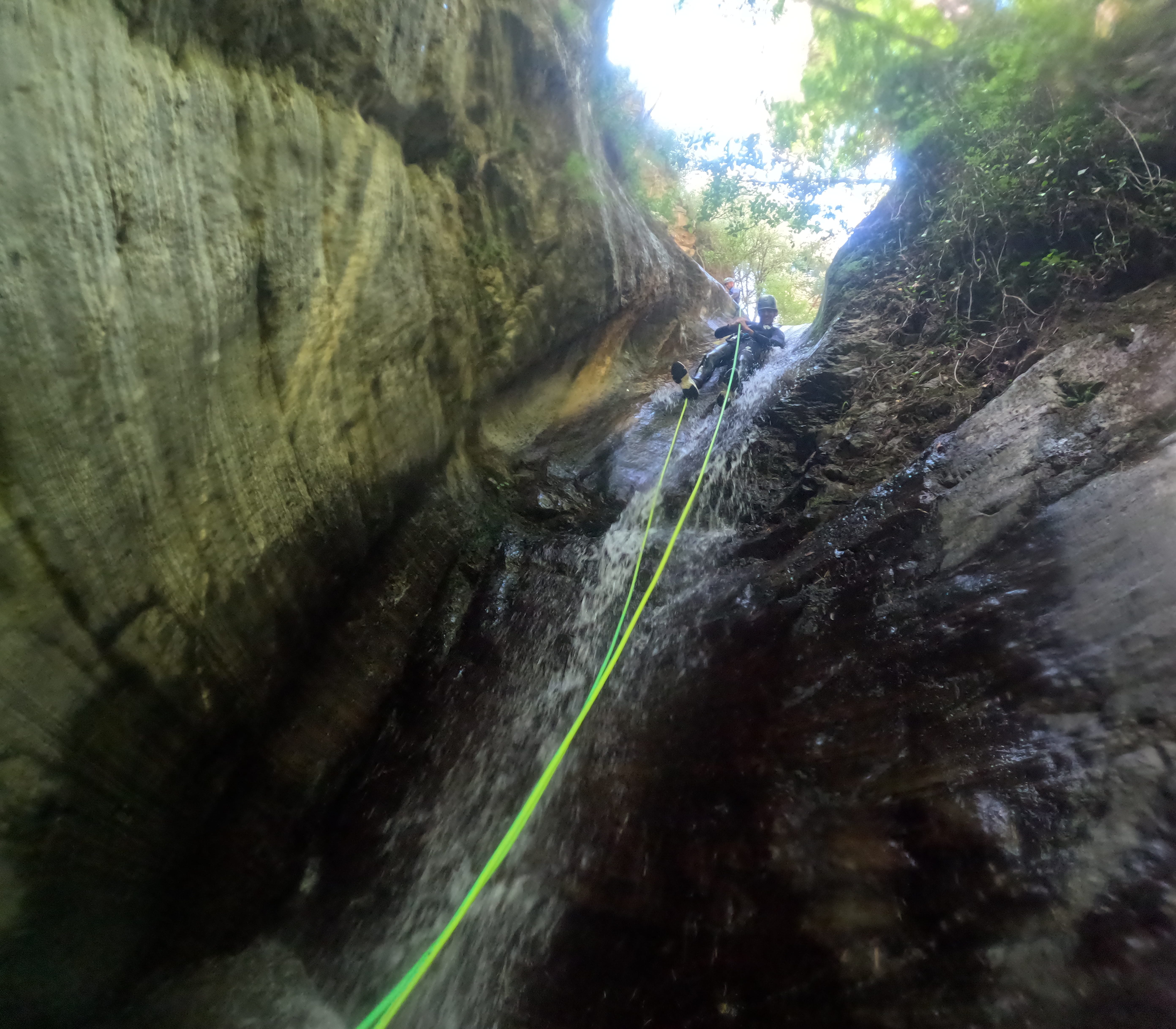Canyoning participant rappelling down a waterfall in a narrow section of Barranco de Estaron