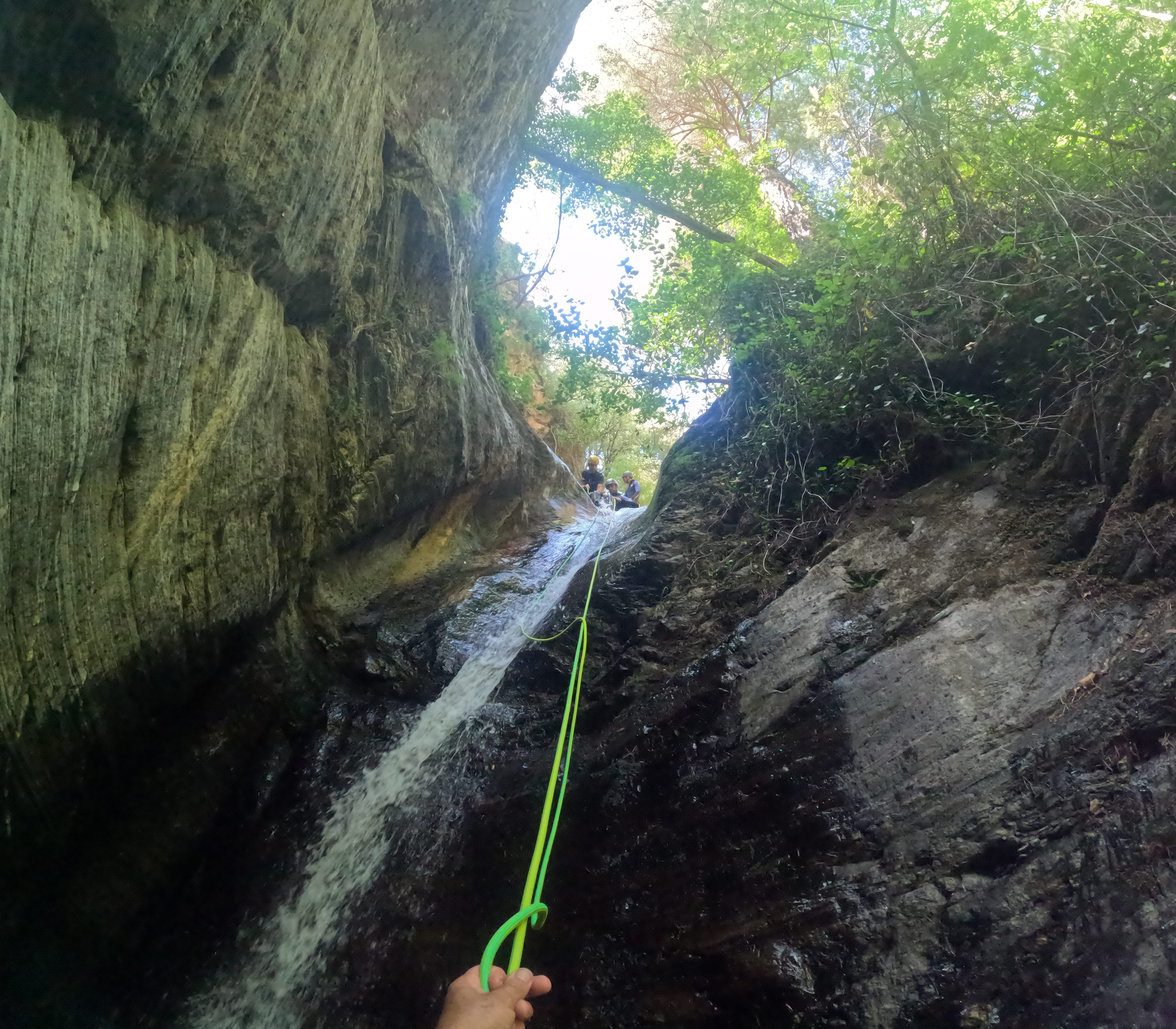 View from below of a canyoning rappel beside a waterfall in Barranco de Estaron