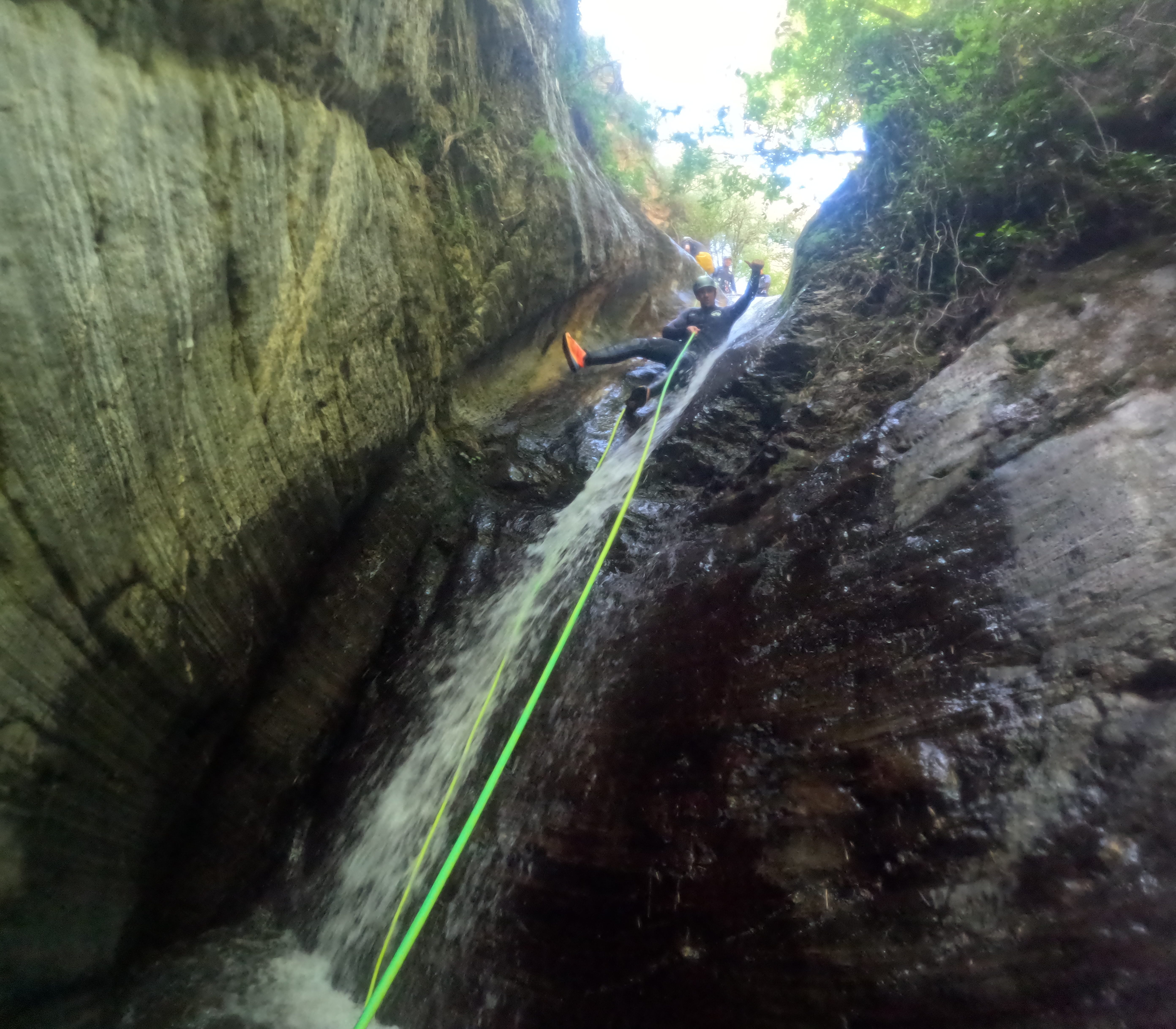 Canyoning participant descending on a rope beside a waterfall in Barranco de Estaron