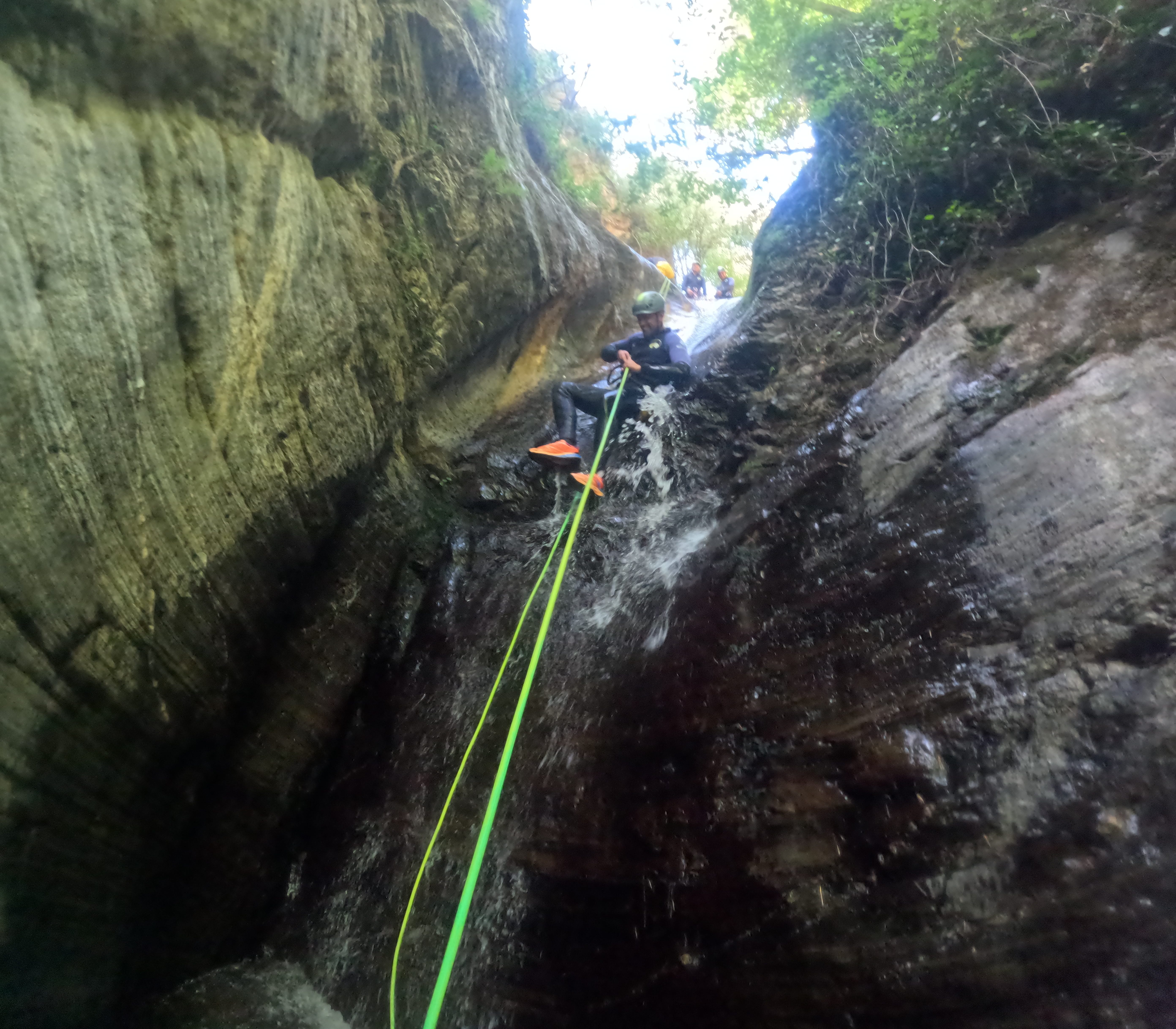 Canyoning participant rappelling down a waterfall with a rope in Barranco de Estaron