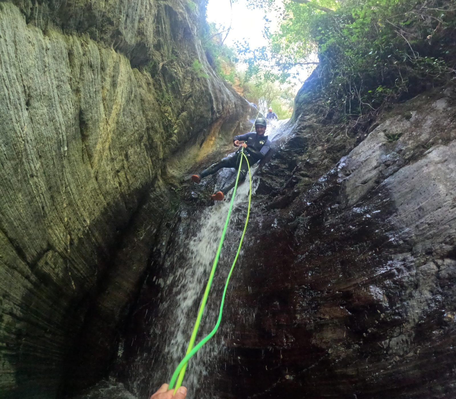Canyoning participant descending on a rope beside a waterfall in Barranco de Estaron