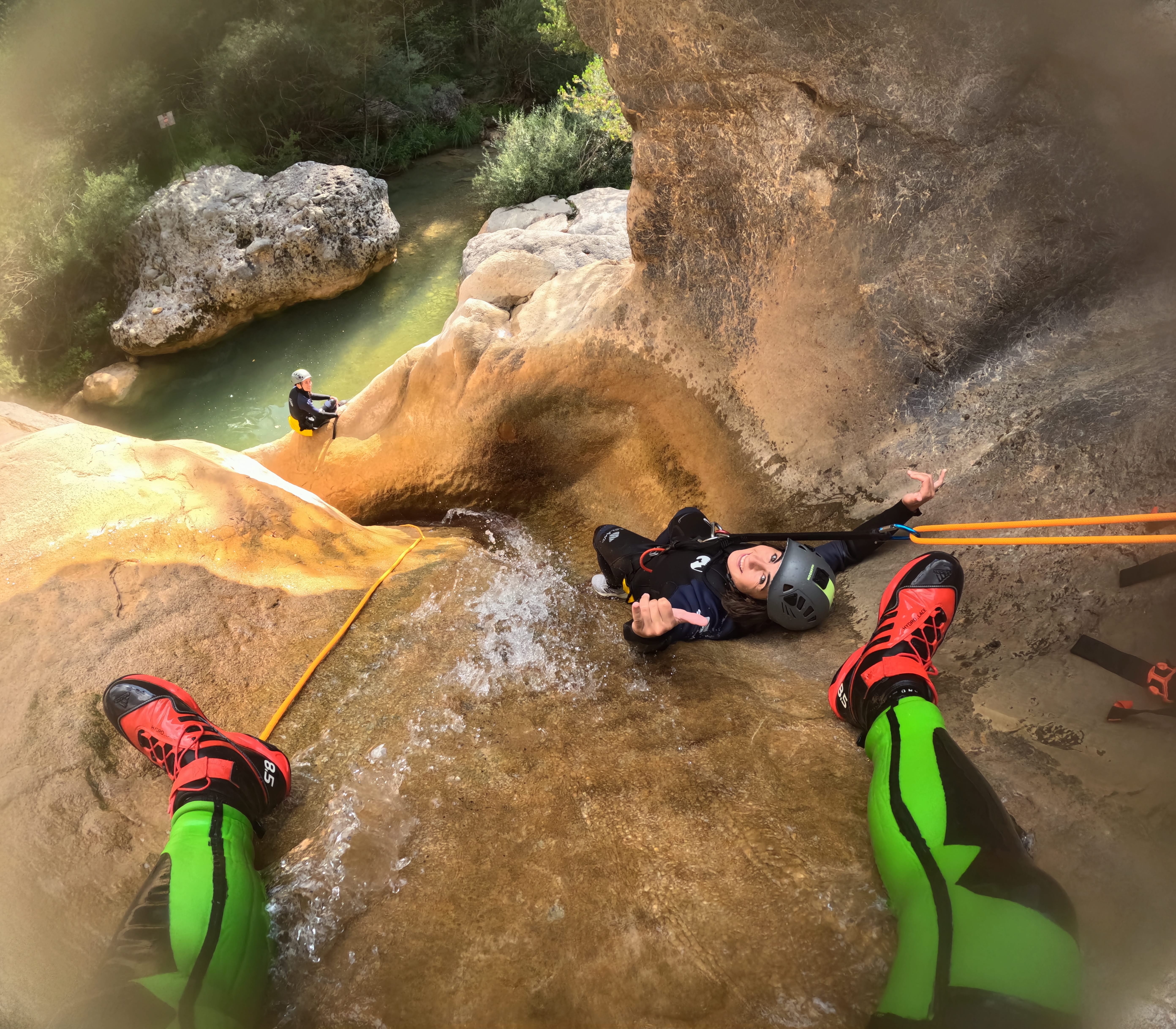 Canyoning participant descending by rope down a wet rock chute in Barranc de Viu de Llevata