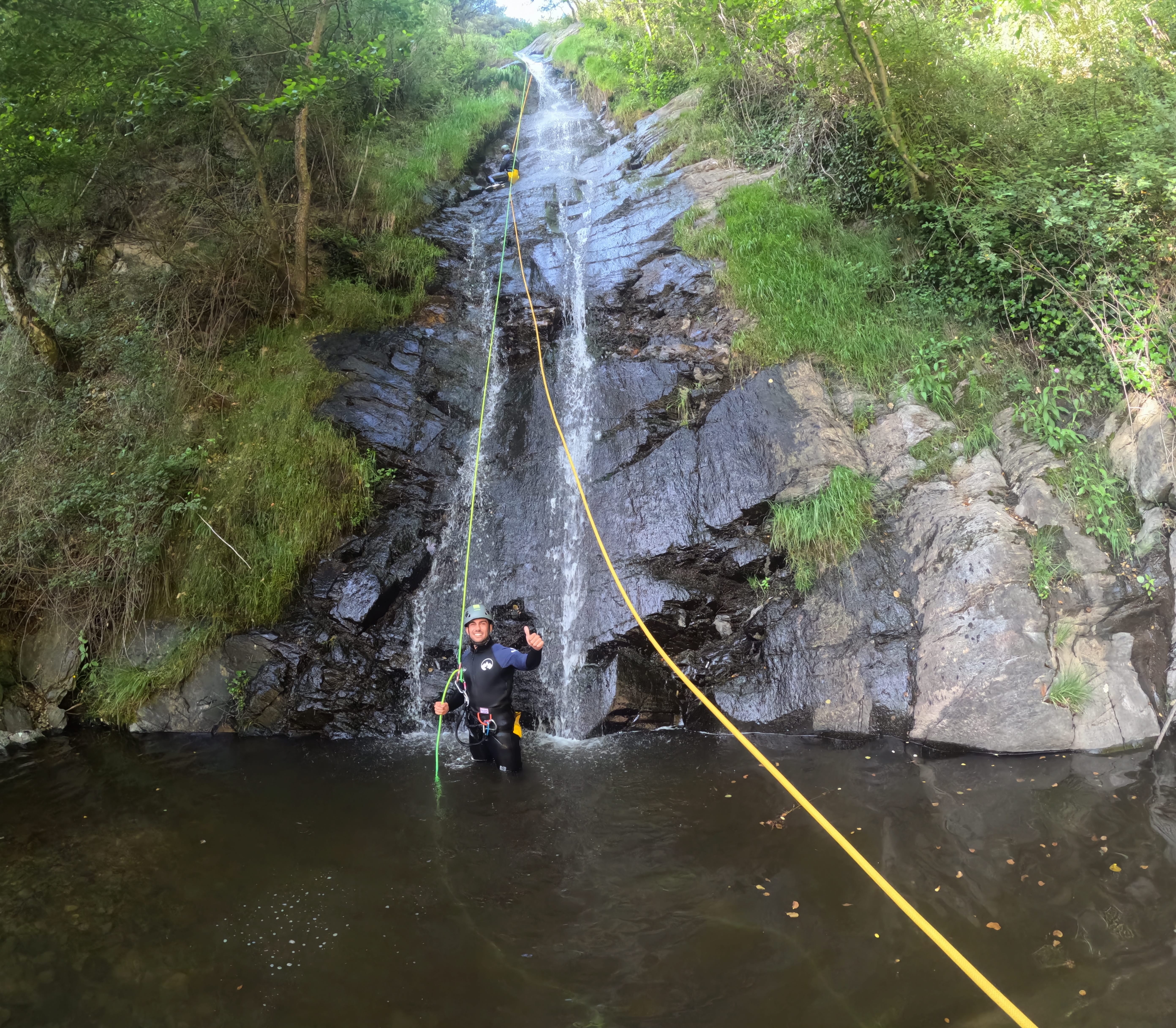 Canyoning participant finishing a long rappel down a waterfall in Barranco de Estaron