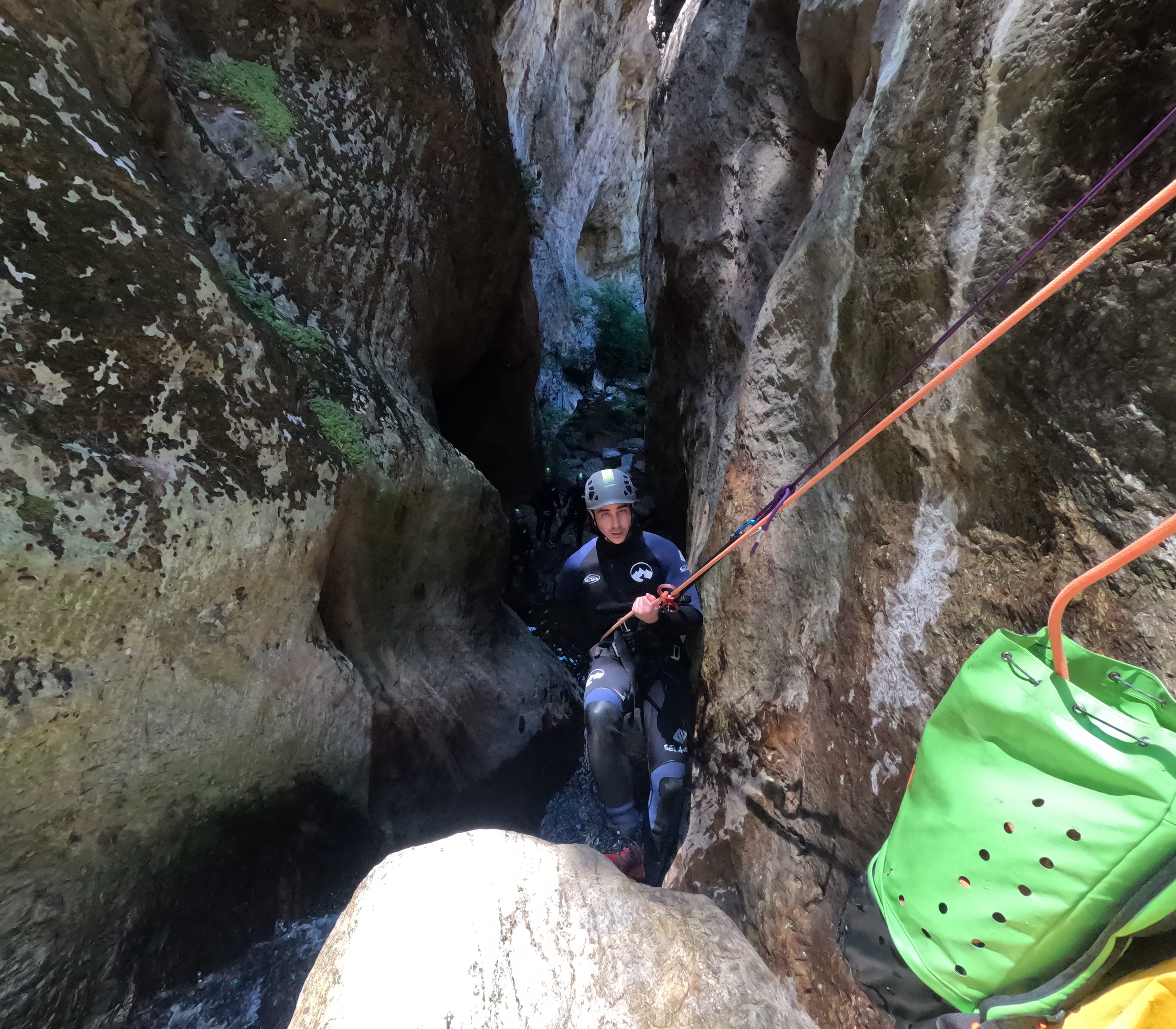 Canyoning participant rappelling through a narrow rocky gorge in Barranco de Estaron