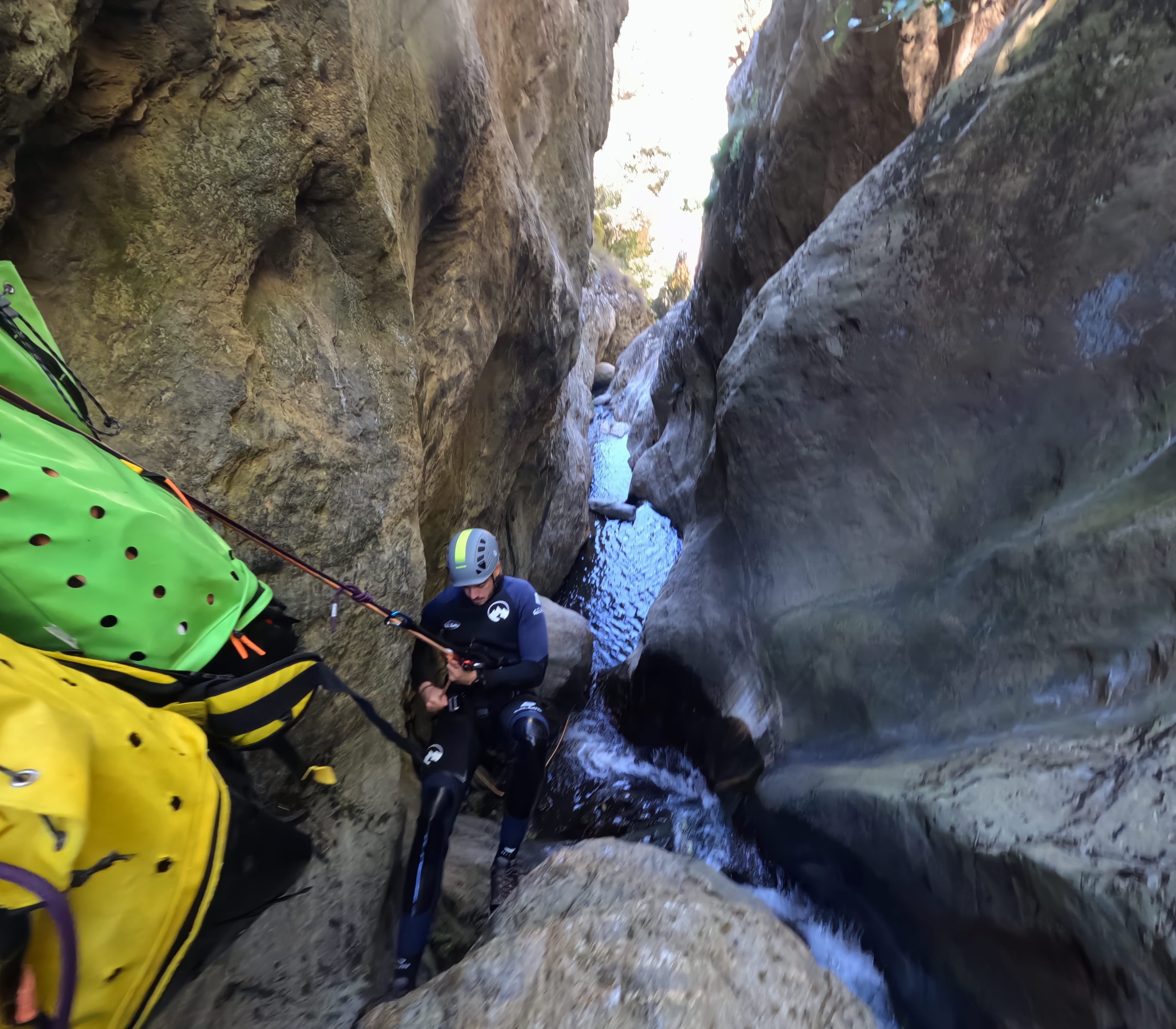 Canyoning participant rappelling through a narrow rocky section of Barranco de Estaron