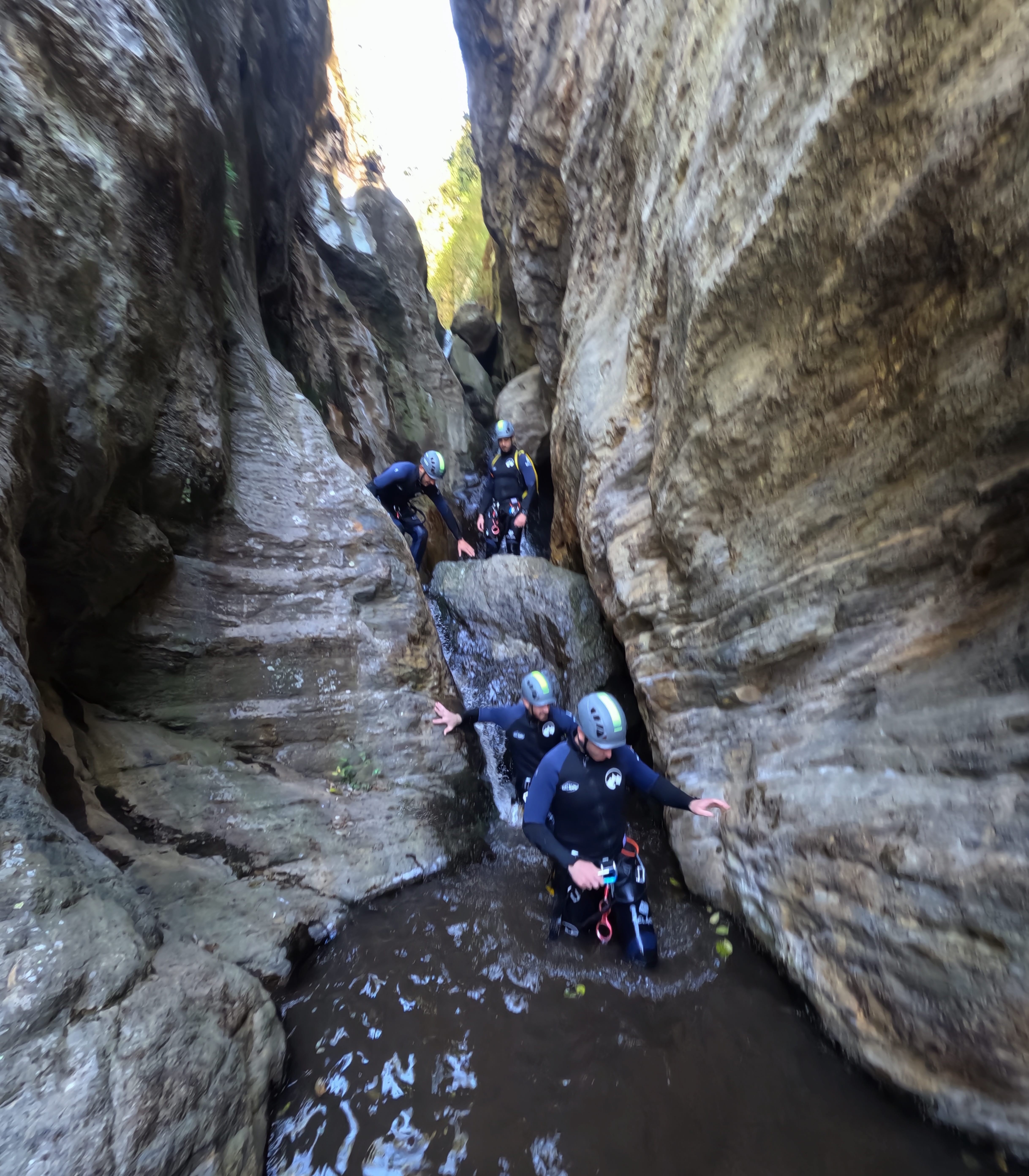 Group of canyoning participants moving through a narrow water-filled gorge in Barranco de Estaron