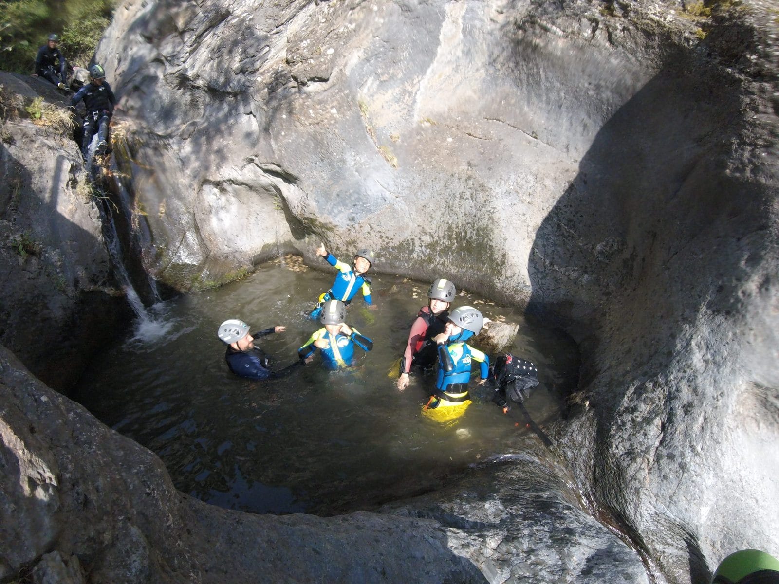 Group of participants in a natural pool between rock walls during a canyoning descent in Barranco de Berrós