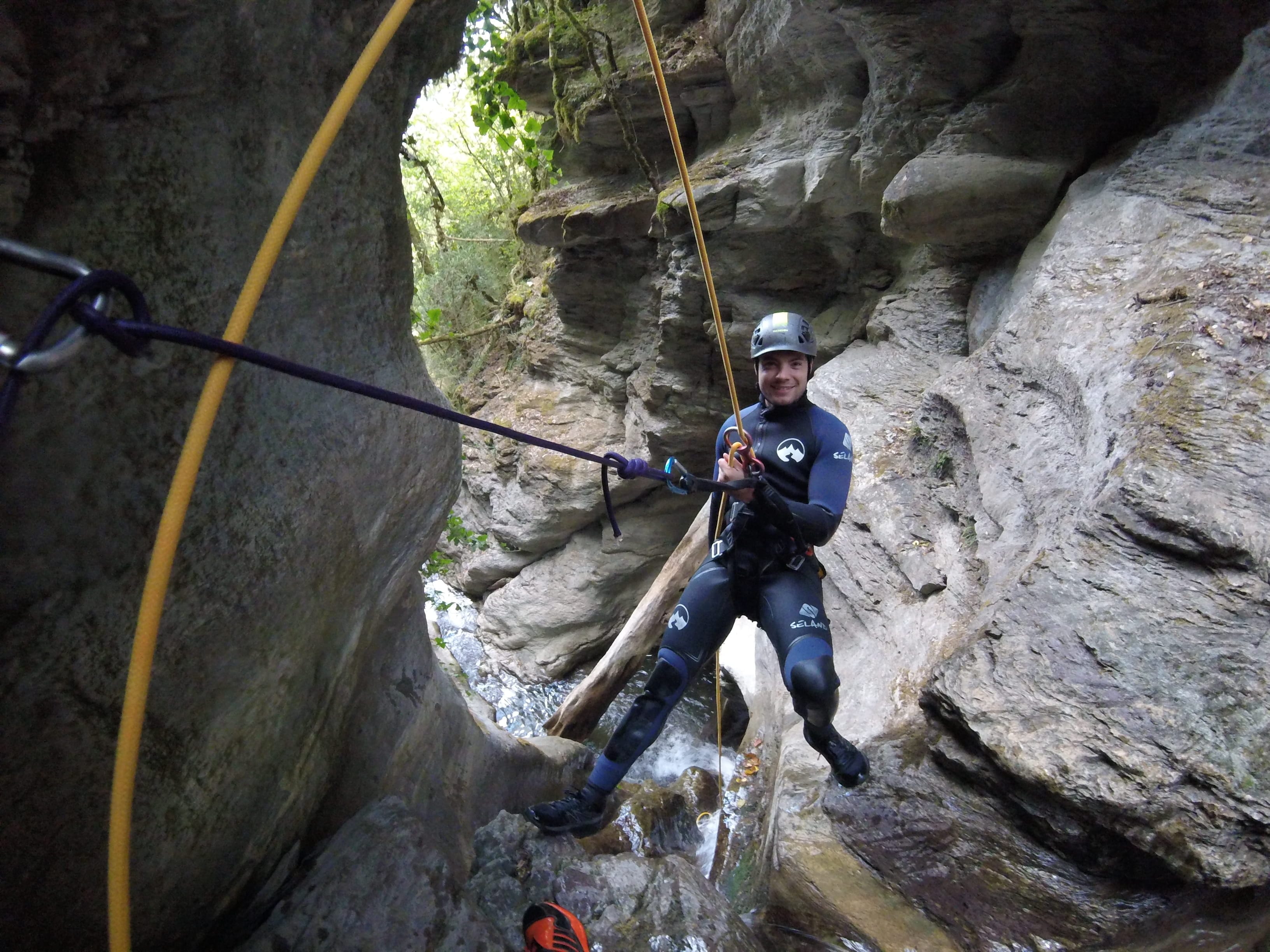 Participant rappelling between narrow rock walls in Les Espones canyon