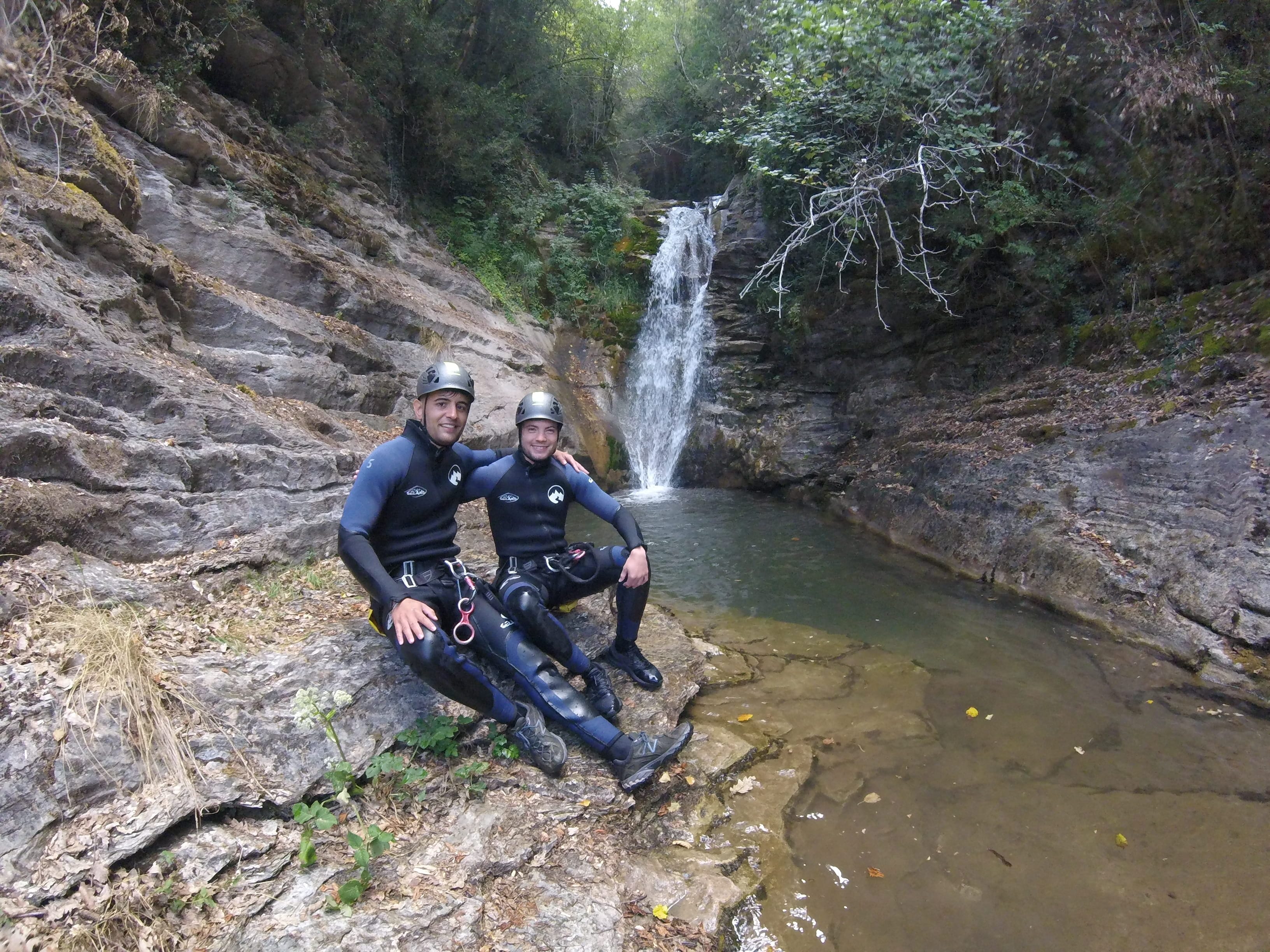 Two participants posing beside a waterfall and natural pool in Les Espones canyon