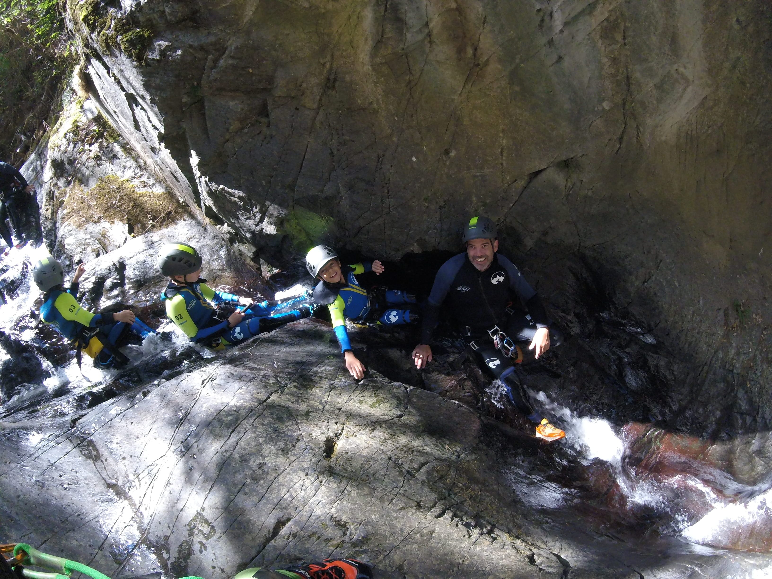 Adults and children moving carefully down a rocky watercourse during a family canyoning descent in Barranco de Berrós