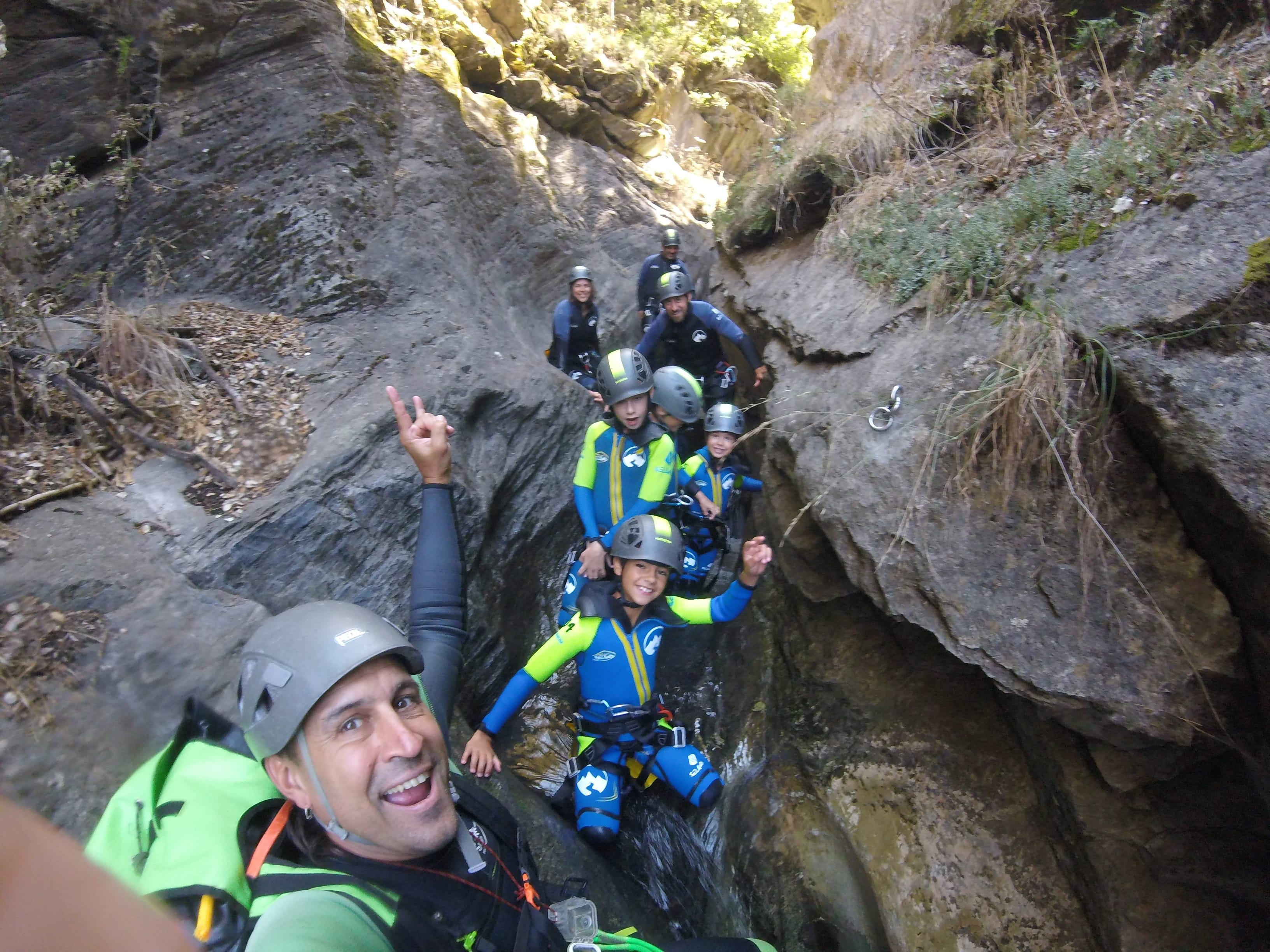 Guide taking a group selfie with adults and children during a family canyoning descent in Barranco de Berrós