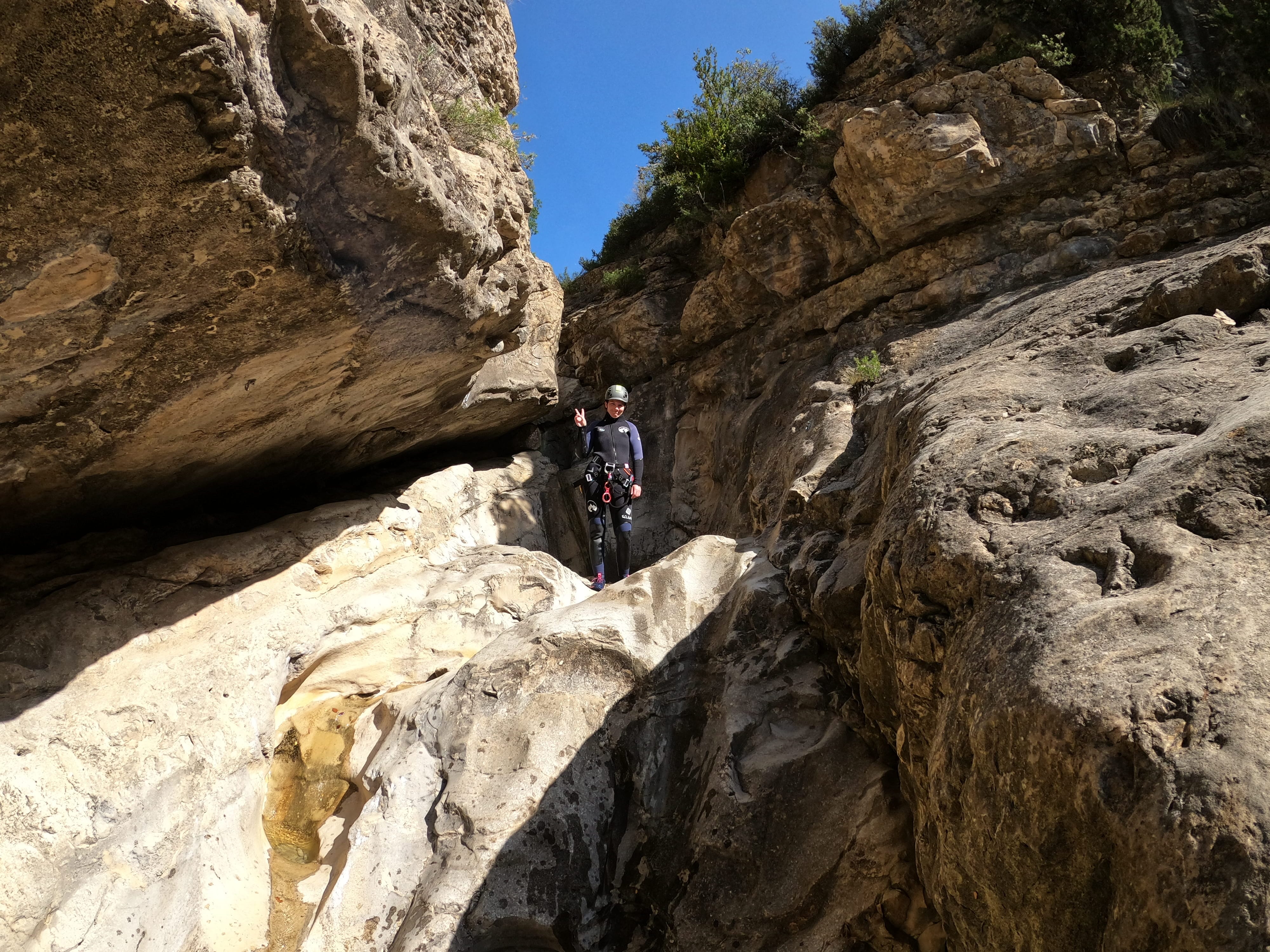 Participant preparing to descend a narrow rocky section of Barranco de Gurp between steep limestone walls