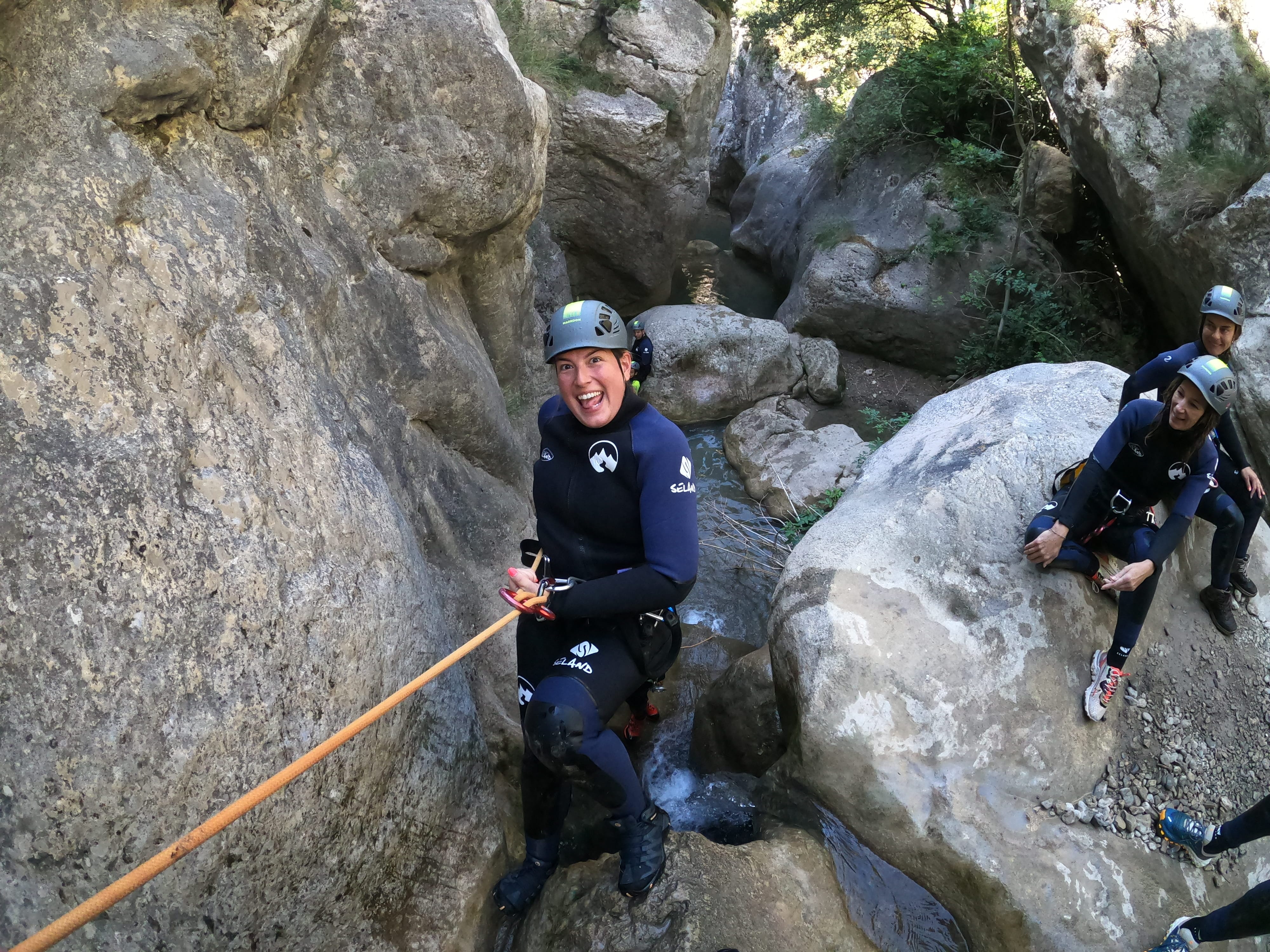 Canyoning participant descending with a rope between large rock formations in Barranco de Bóixols
