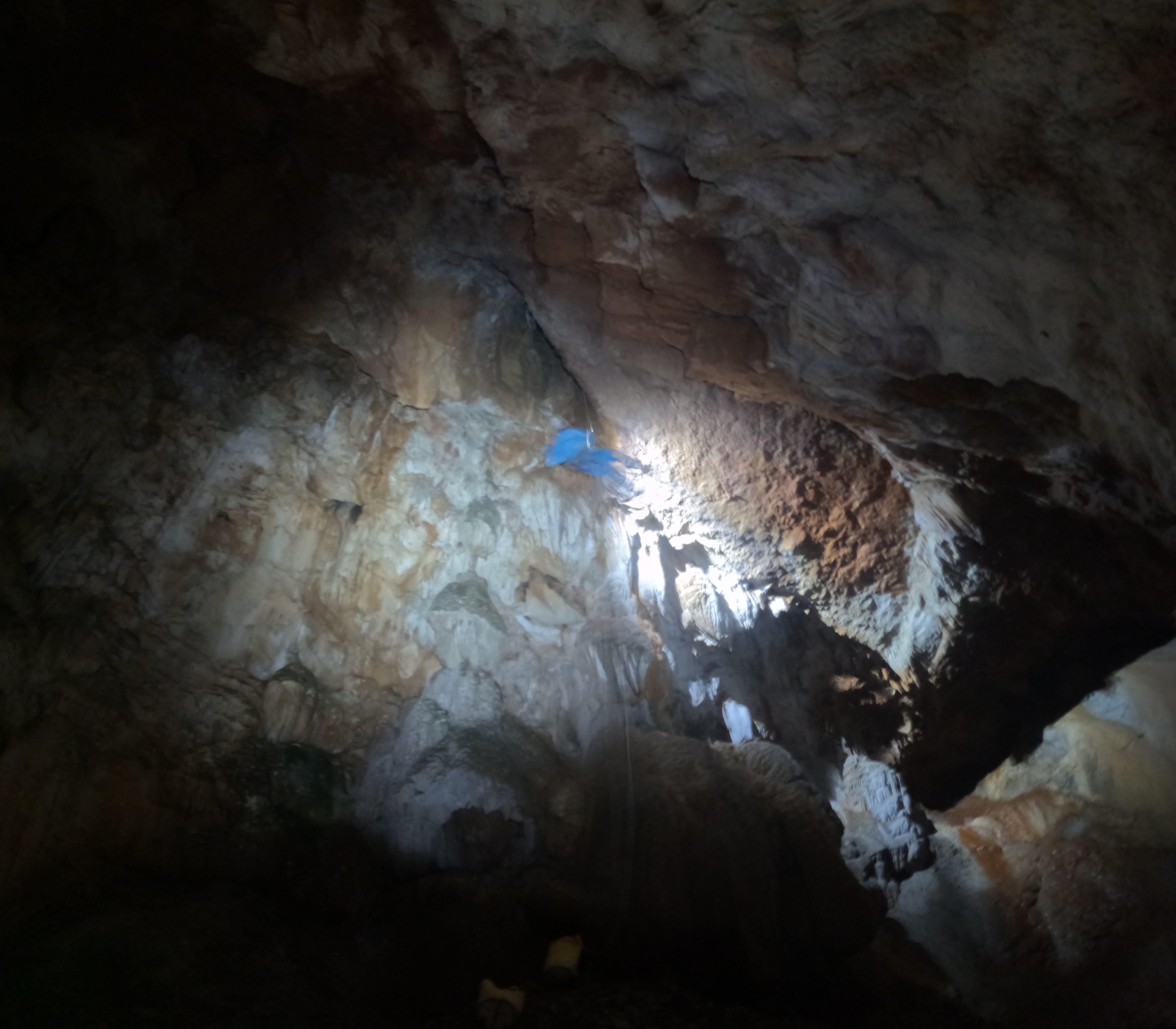 Espeleólogo ascendiendo por una gran sala vertical iluminada por los frontales en el interior de la Sima Forat dels Diners