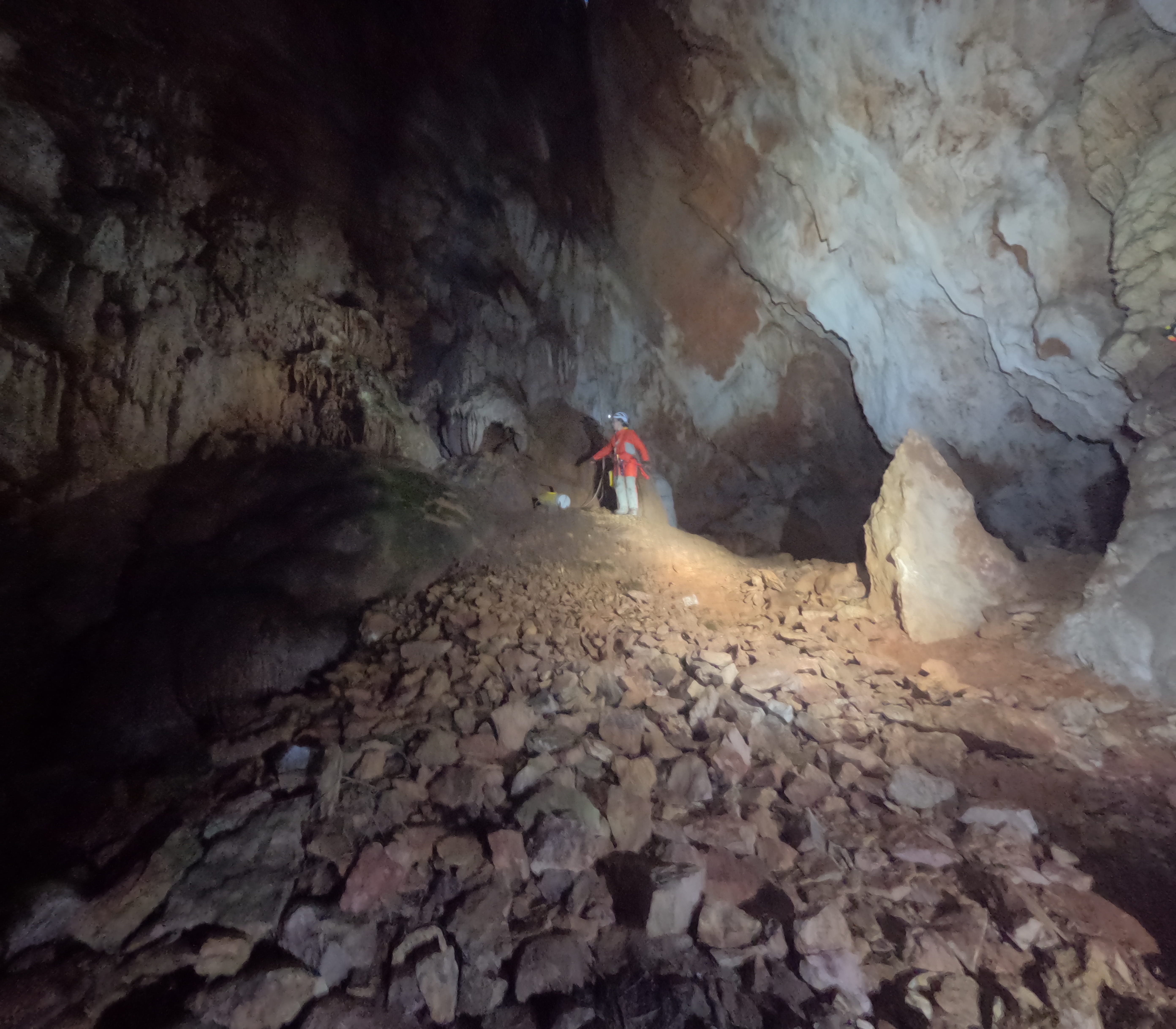 Espeleólogo explorando una gran sala rocosa de paredes altas en el interior de la Sima Forat dels Diners