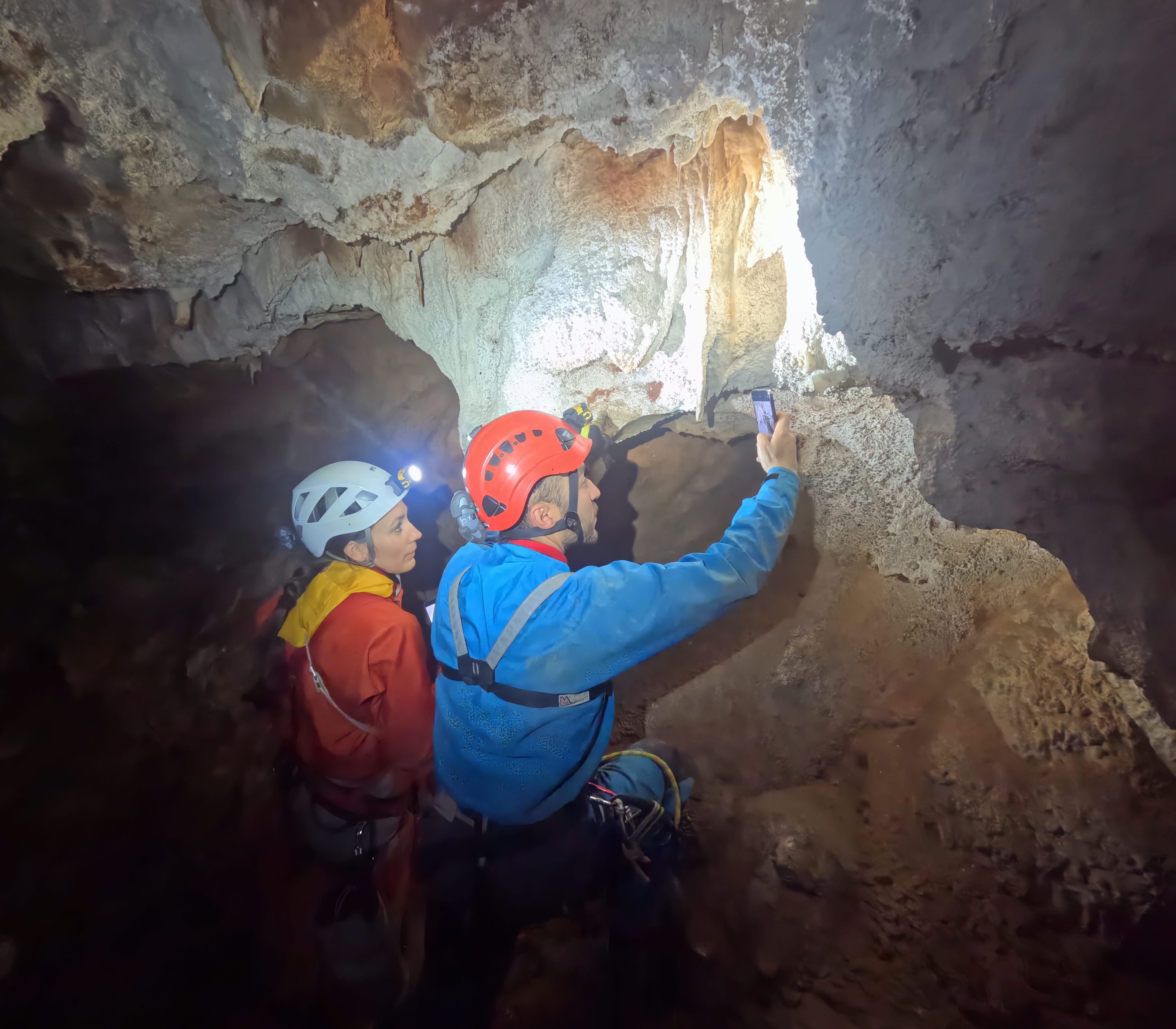 Espeleólogos observando y fotografiando delicadas formaciones minerales en el interior de la Sima Forat dels Diners