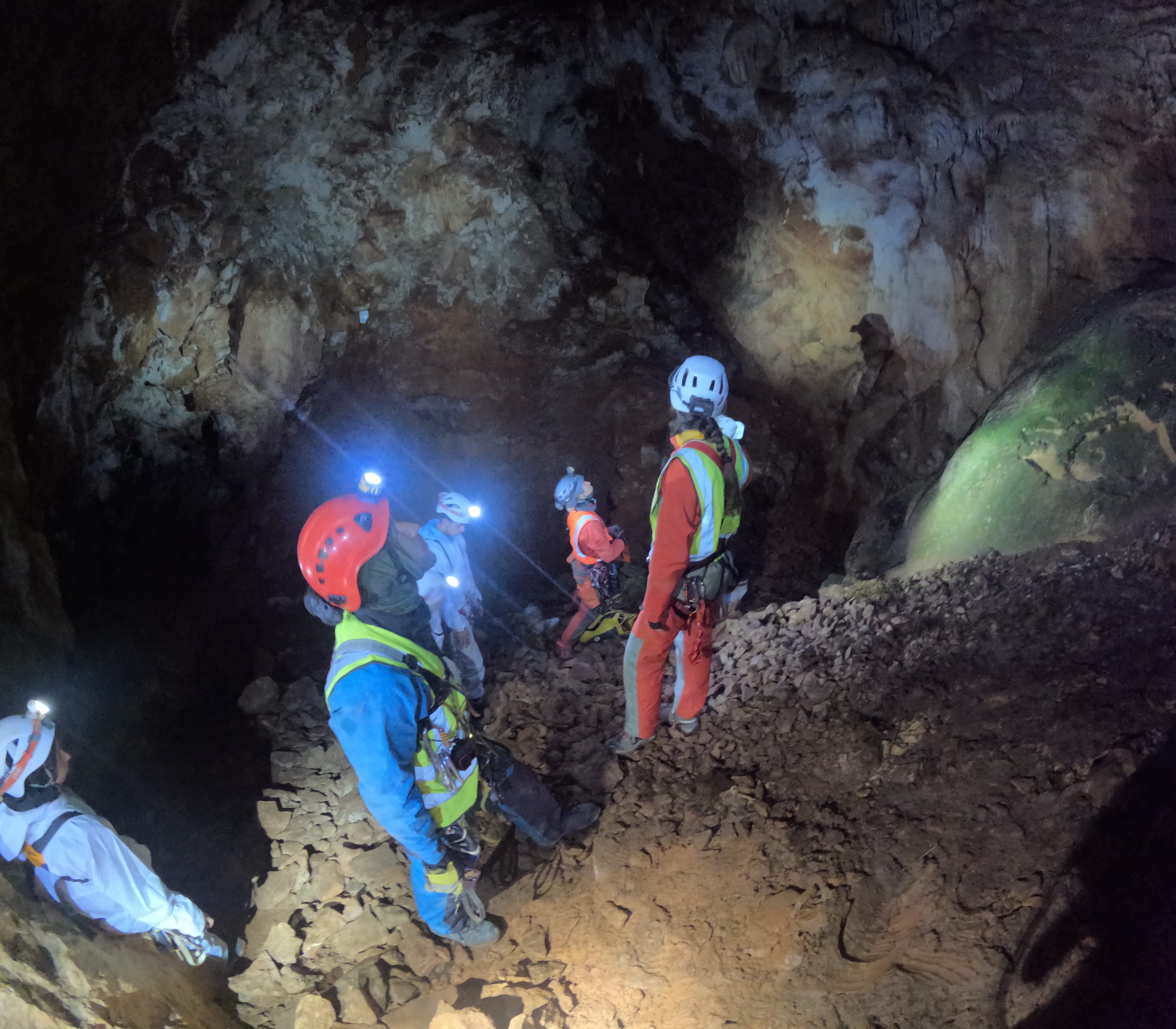 Grupo de espeleólogos explorando una sala subterránea rocosa con luces frontales en el interior de la Sima Forat dels Diners
