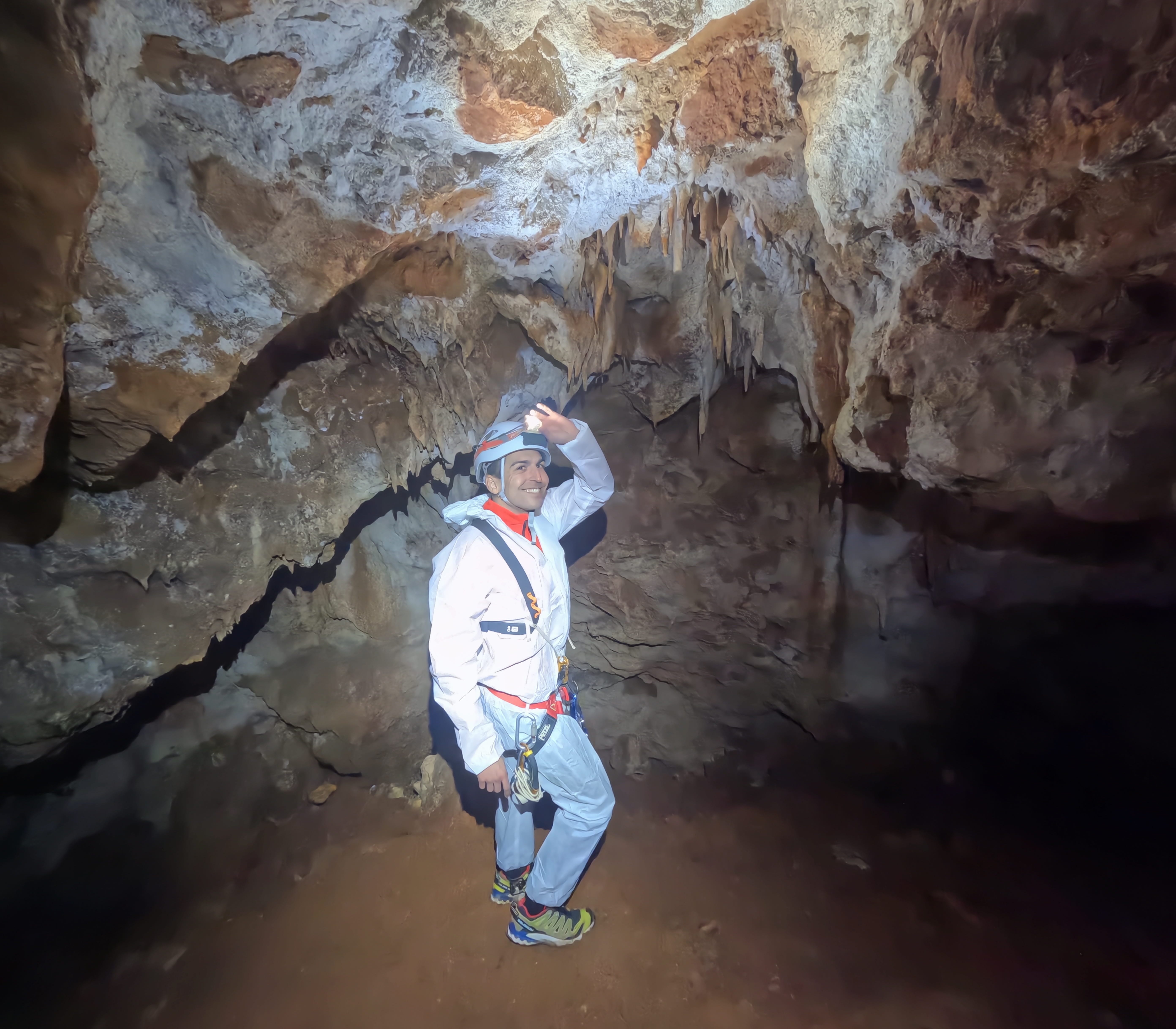 Espeleólogo explorando una sala con estalactitas y formaciones de calcita en el interior de la Sima Forat dels Diners
