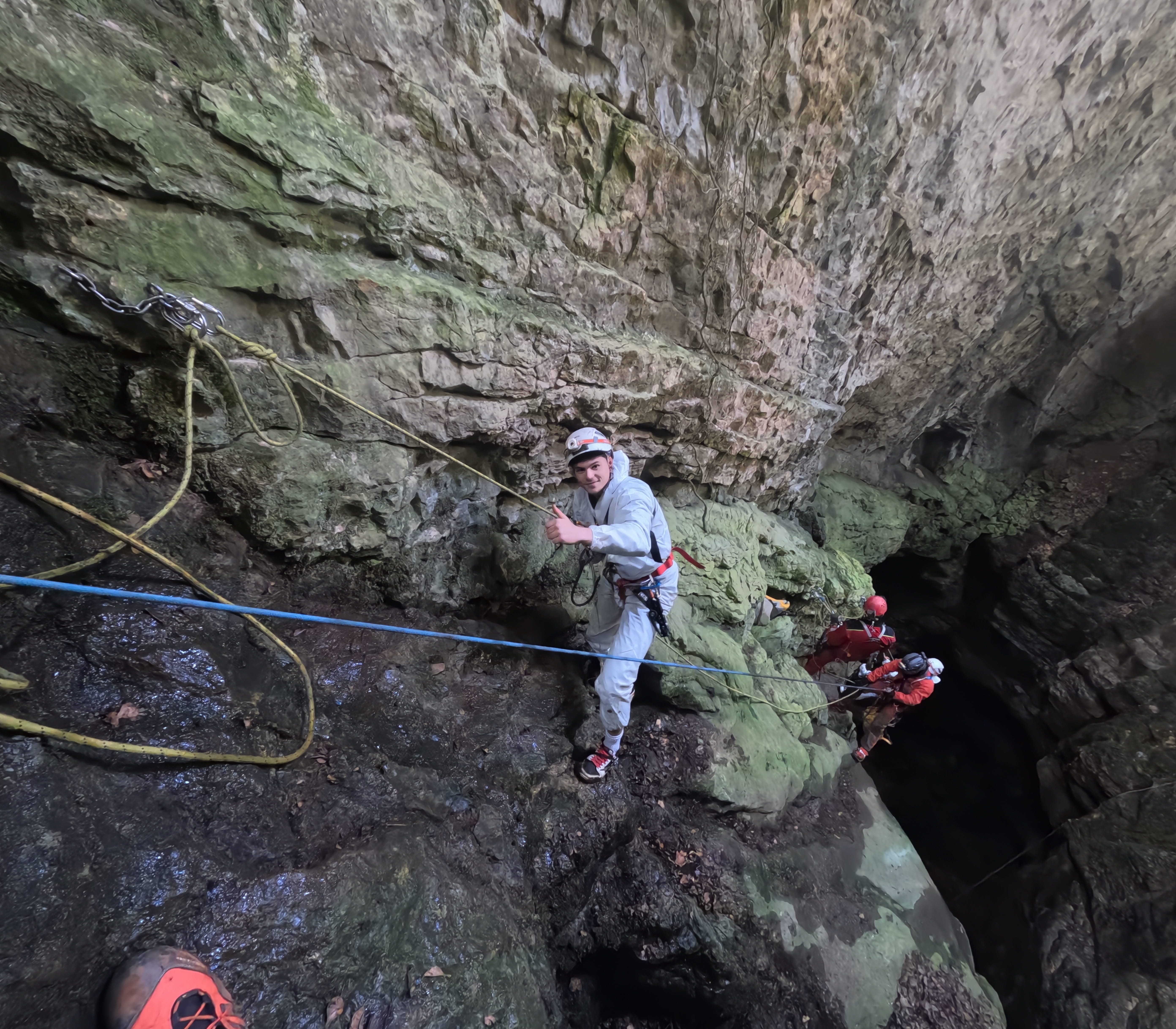 Espeleólogos avanzando por un tramo asegurado con cuerdas sobre el pozo vertical de la Sima Forat dels Diners