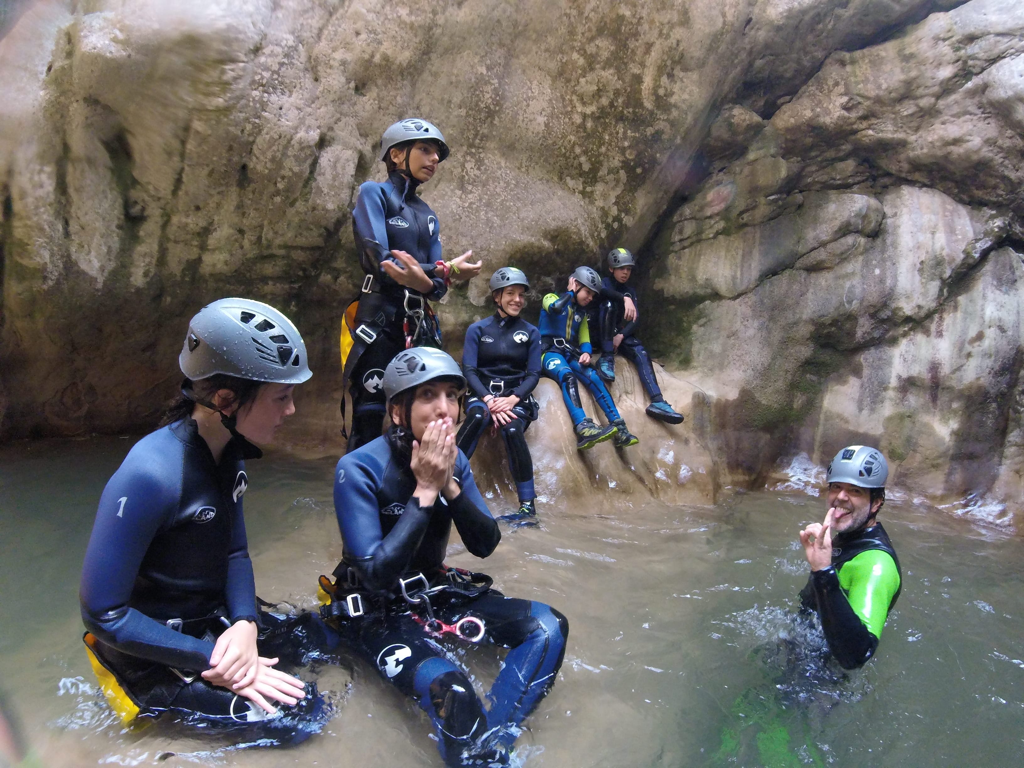 Canyoning group taking a break in a natural pool surrounded by smooth rock walls in Barranc de Viu de Llevata