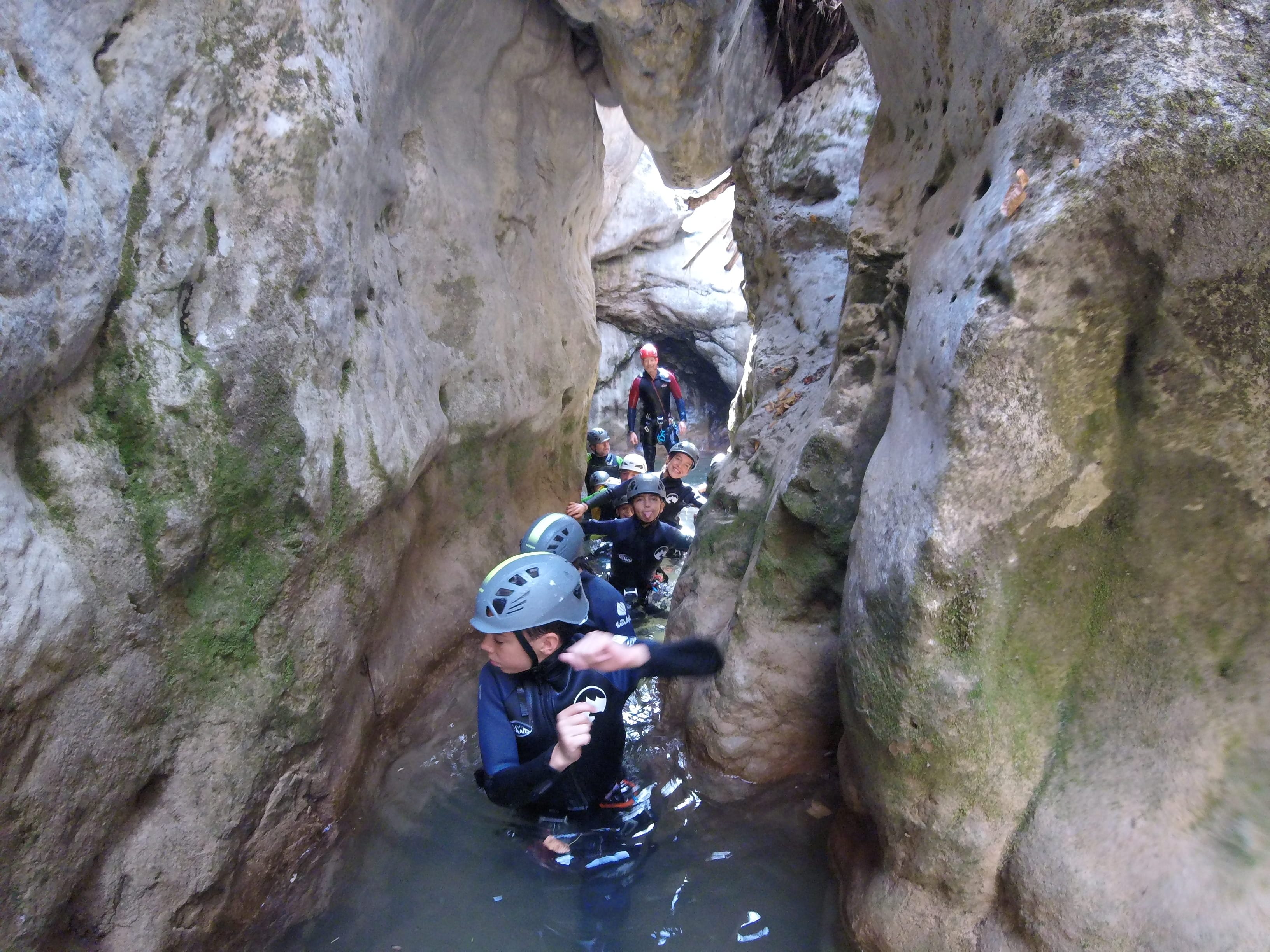 Canyoning group moving through a narrow water-filled rock corridor in Barranc de Viu de Llevata