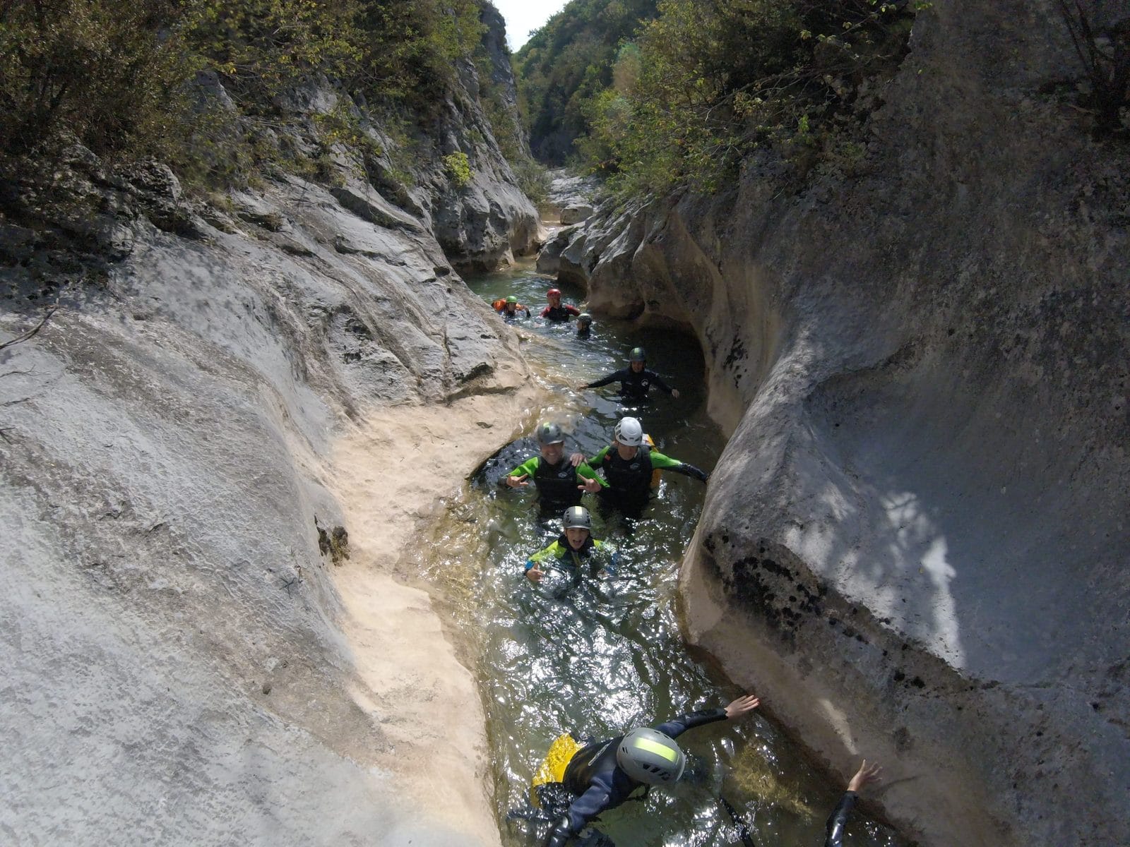 Group canyoning through a long narrow water-filled gorge with smooth rock walls in Barranc de Viu de Llevata