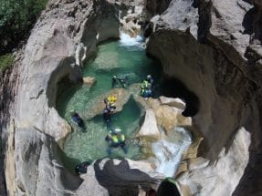 Group canyoning through turquoise pools and waterfalls in Peonera Canyon