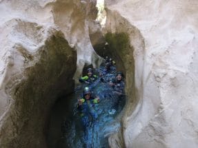 Group canyoning through a narrow water passage in Peonera Canyon