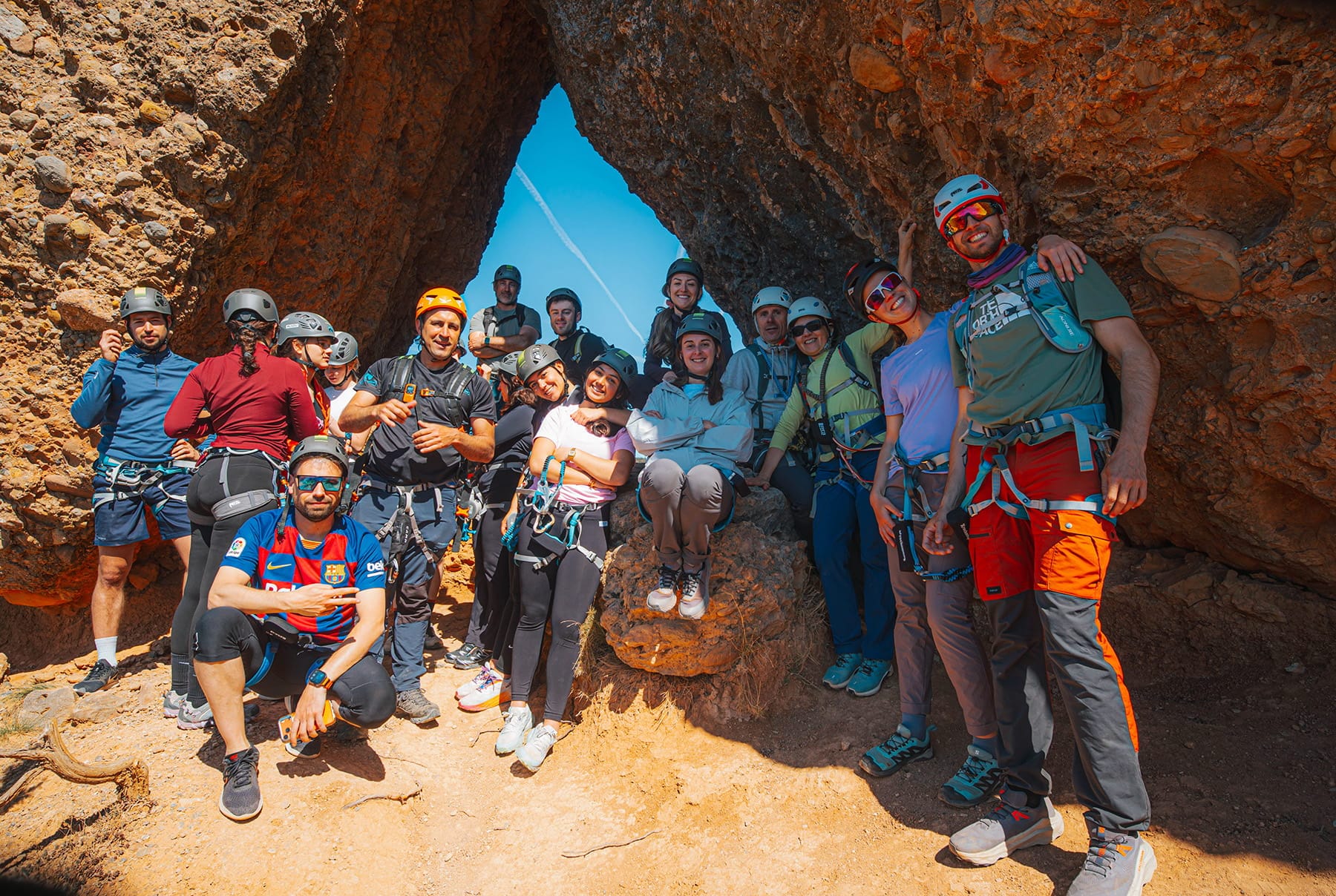 Group of participants posing together inside the natural rock arch of the Vía Ferrata Roca Foradada near La Pobla de Segur